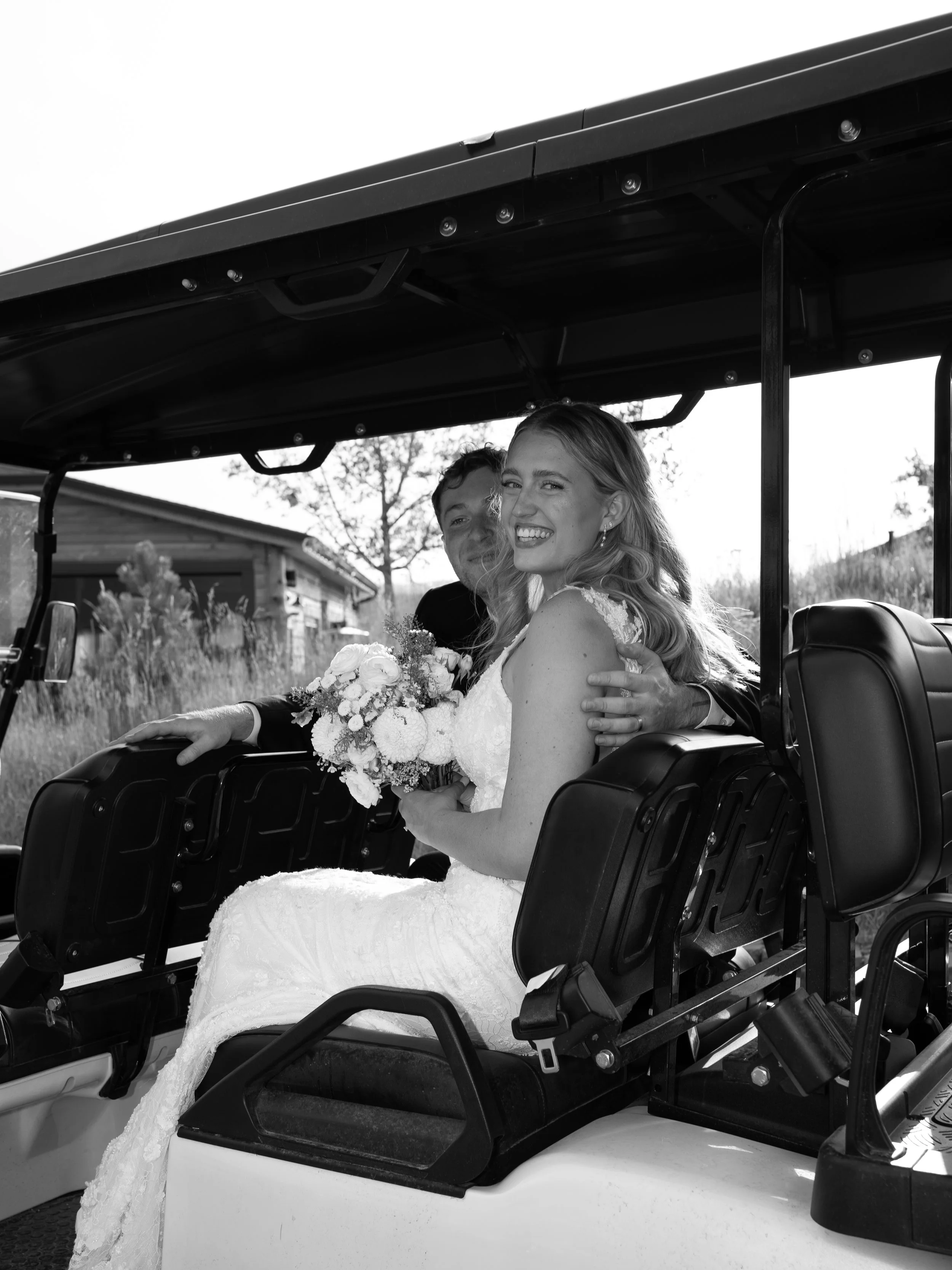 A joyful black-and-white moment in Woodland Park, CO, as the bride rides through the venue with carefree energy.