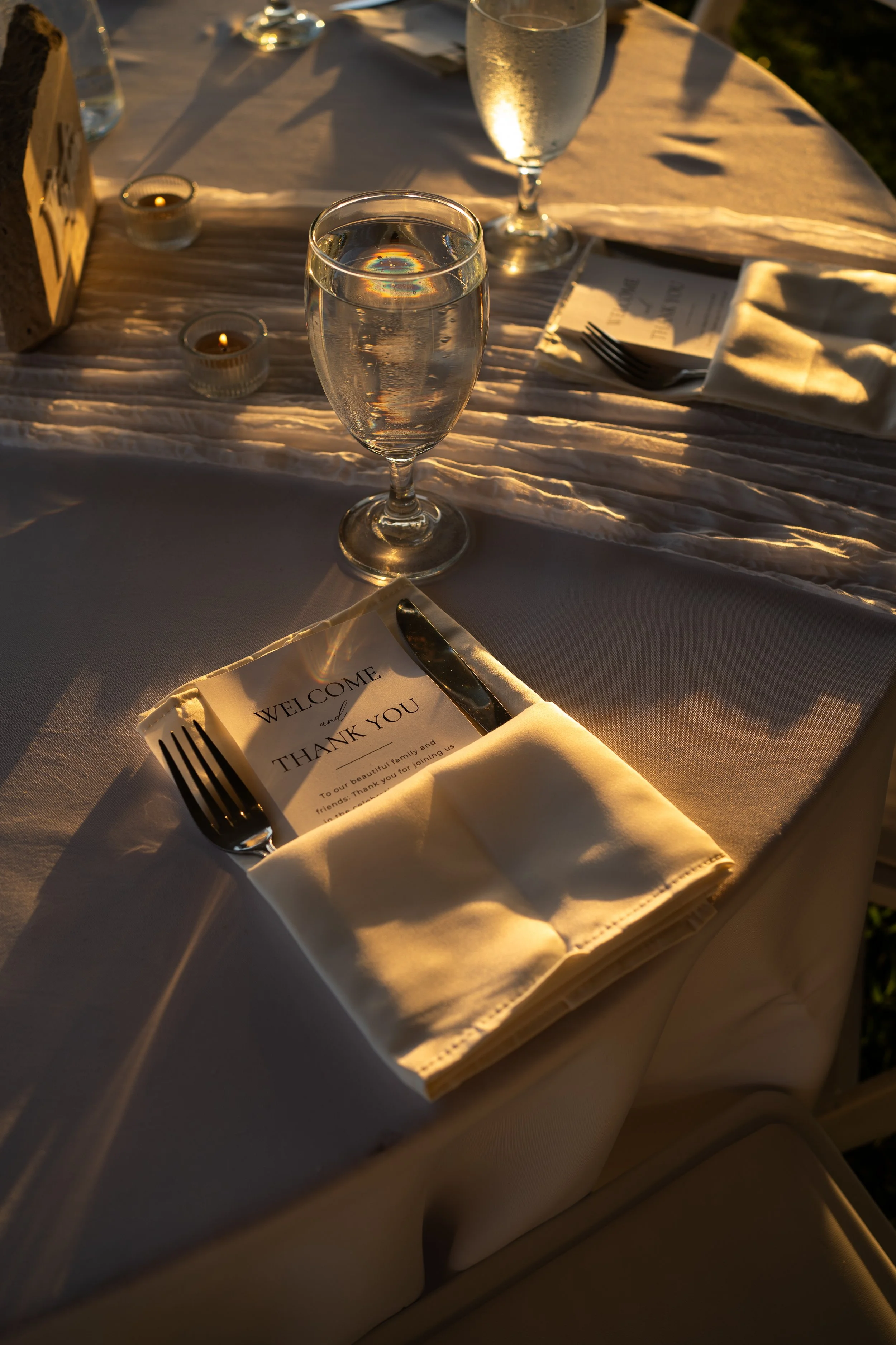 Wedding dinner table details captured in warm light during a backyard tent wedding in Fort Worth, Texas.