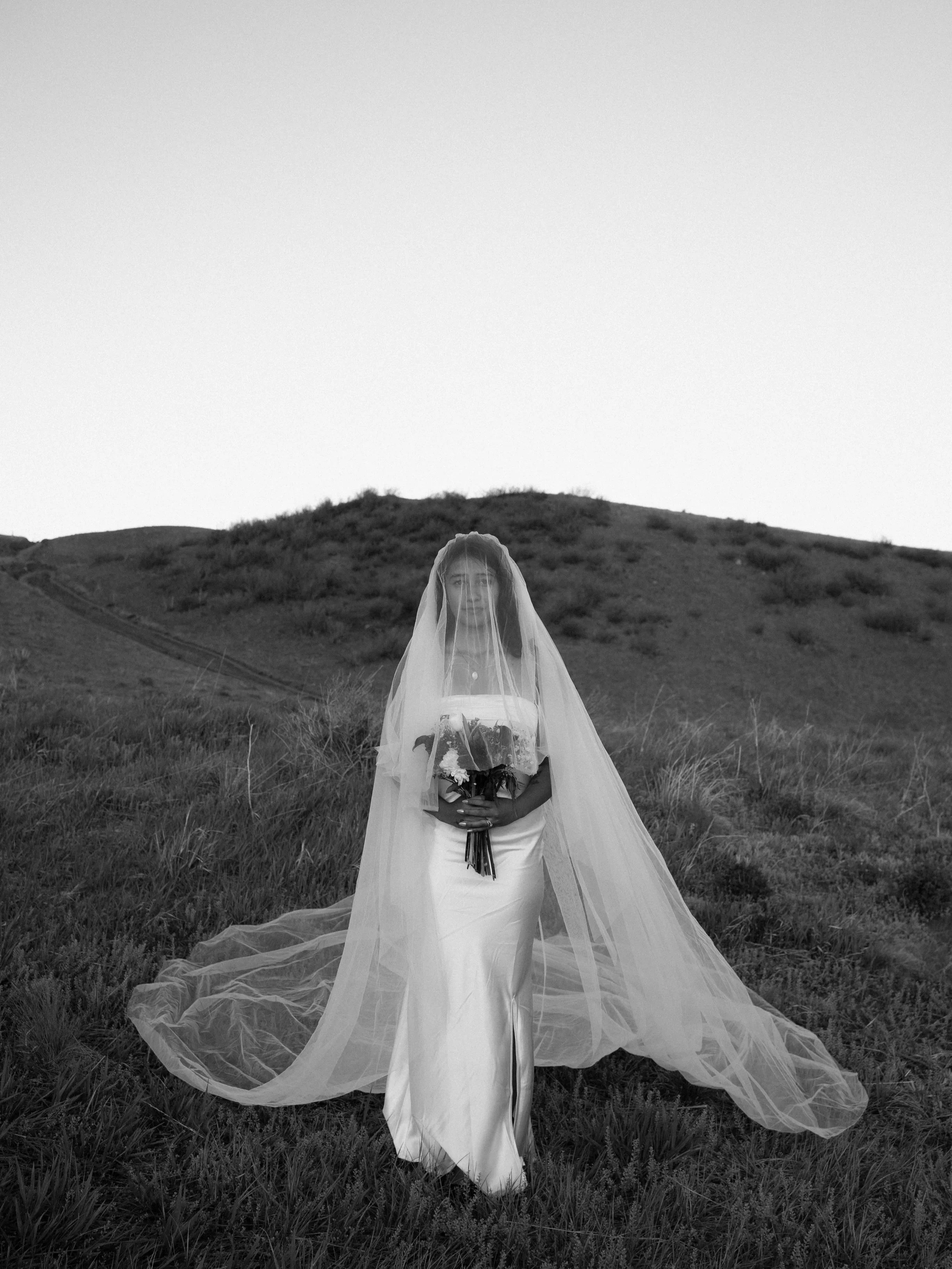 Bride standing in a mountain landscape in Boulder Colorado with her veil moving in the wind