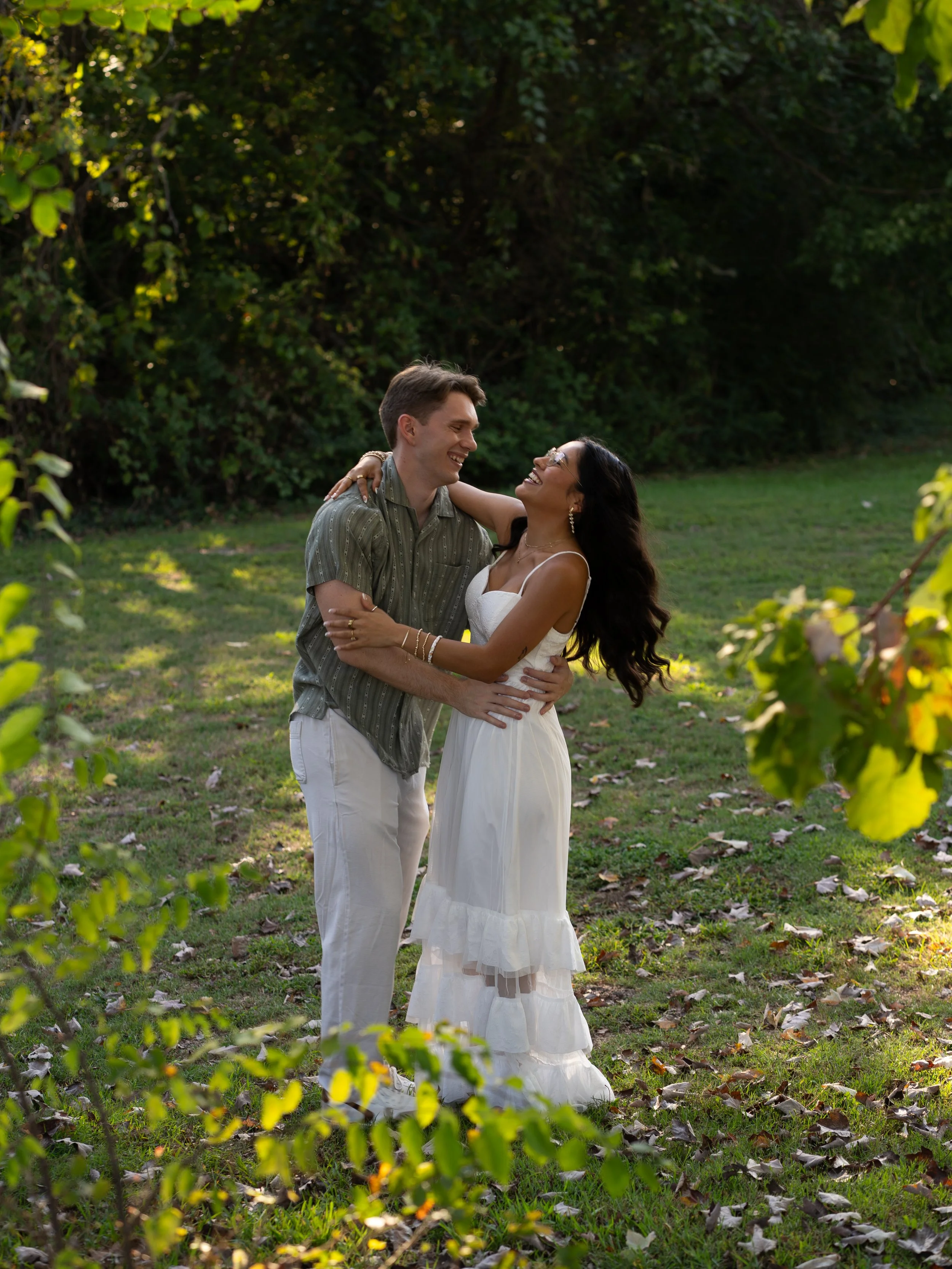 A warm, sunlit engagement moment in Mammoth Spring, Arkansas, capturing playful connection and natural movement.