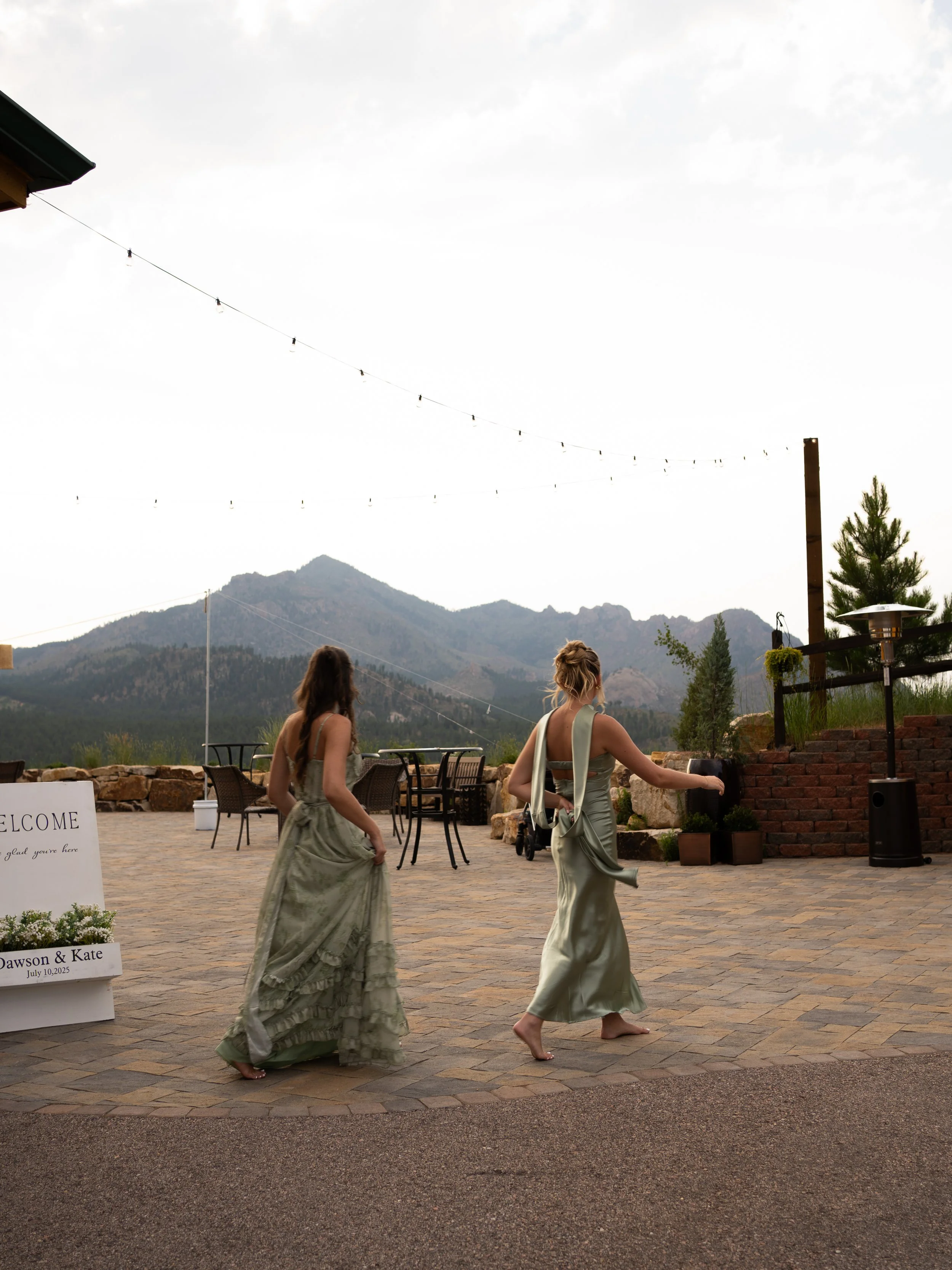A scenic moment at Pikes Peak Ranch, capturing bridesmaids walking beneath open skies with the Colorado mountains in the distance.