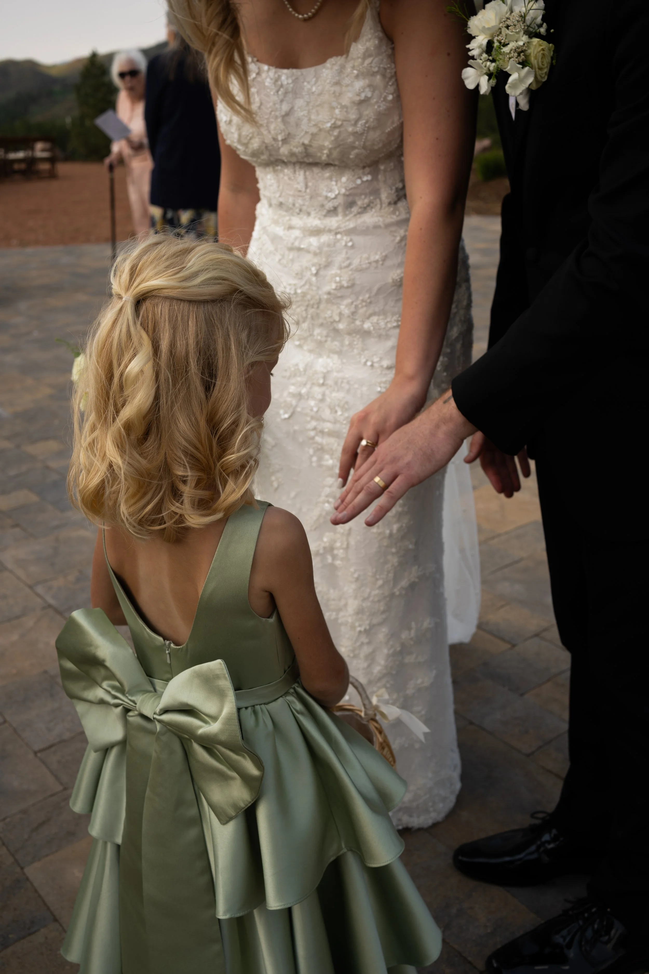 A tender interaction at Pikes Peak Ranch, capturing a quiet and meaningful moment between the couple and a flower girl.