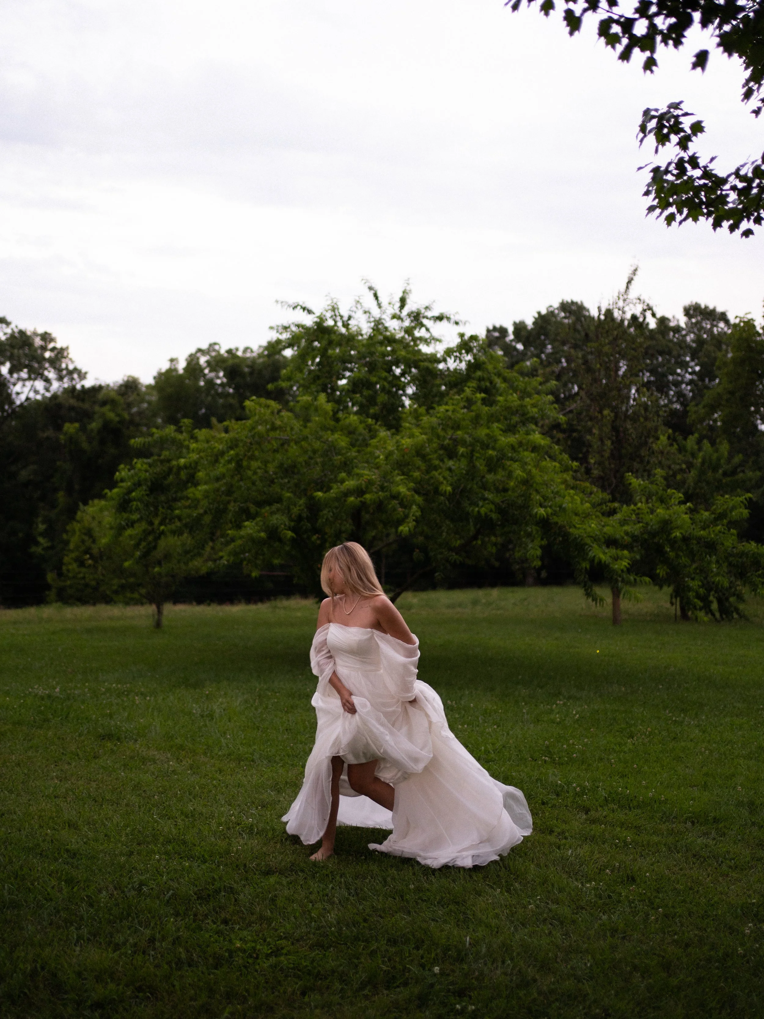 Bride in dress dancing in a lush green field portrait 