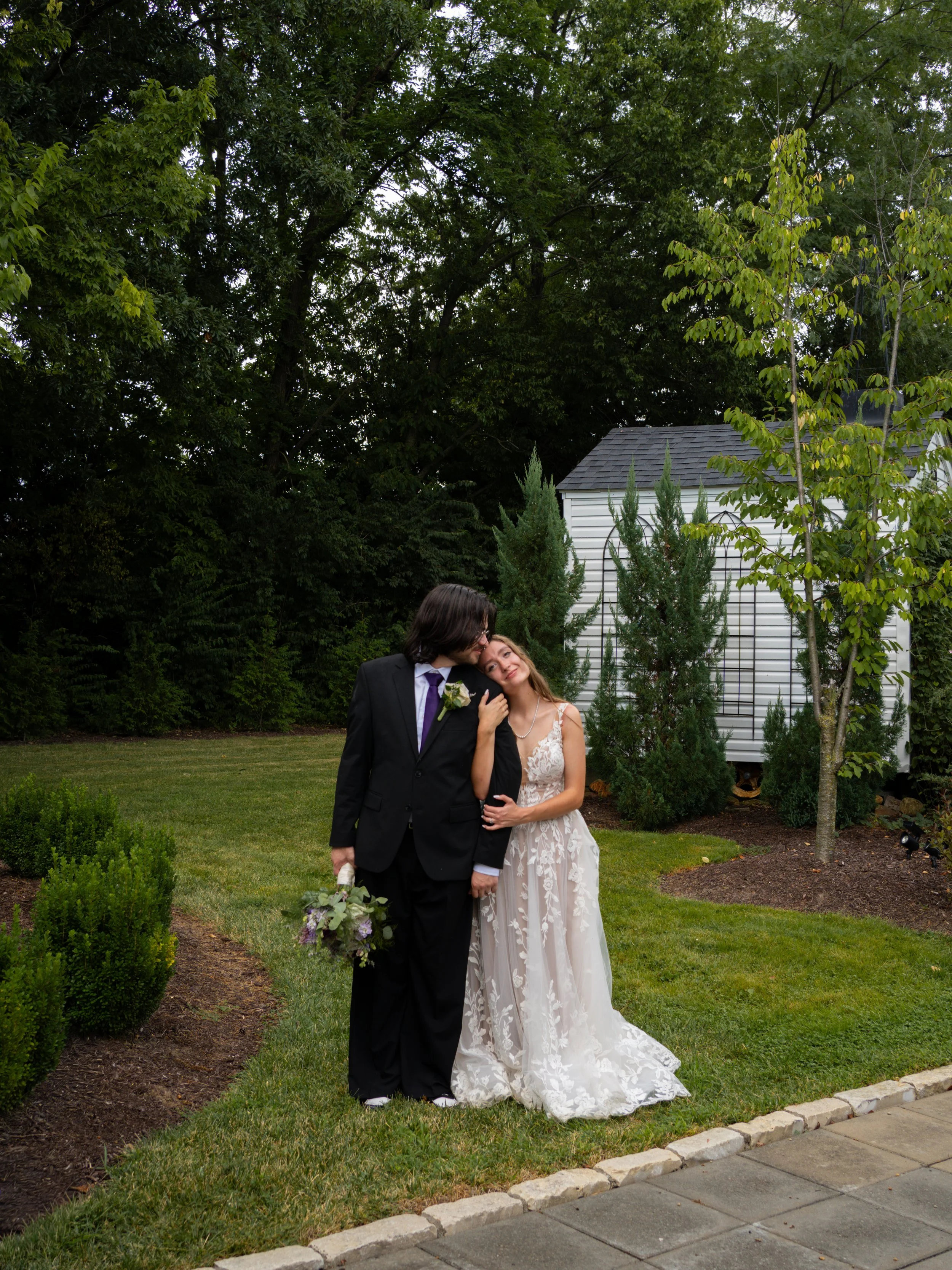 A romantic portrait in O’Fallon, Missouri, capturing the couple in a quiet garden setting surrounded by greenery.