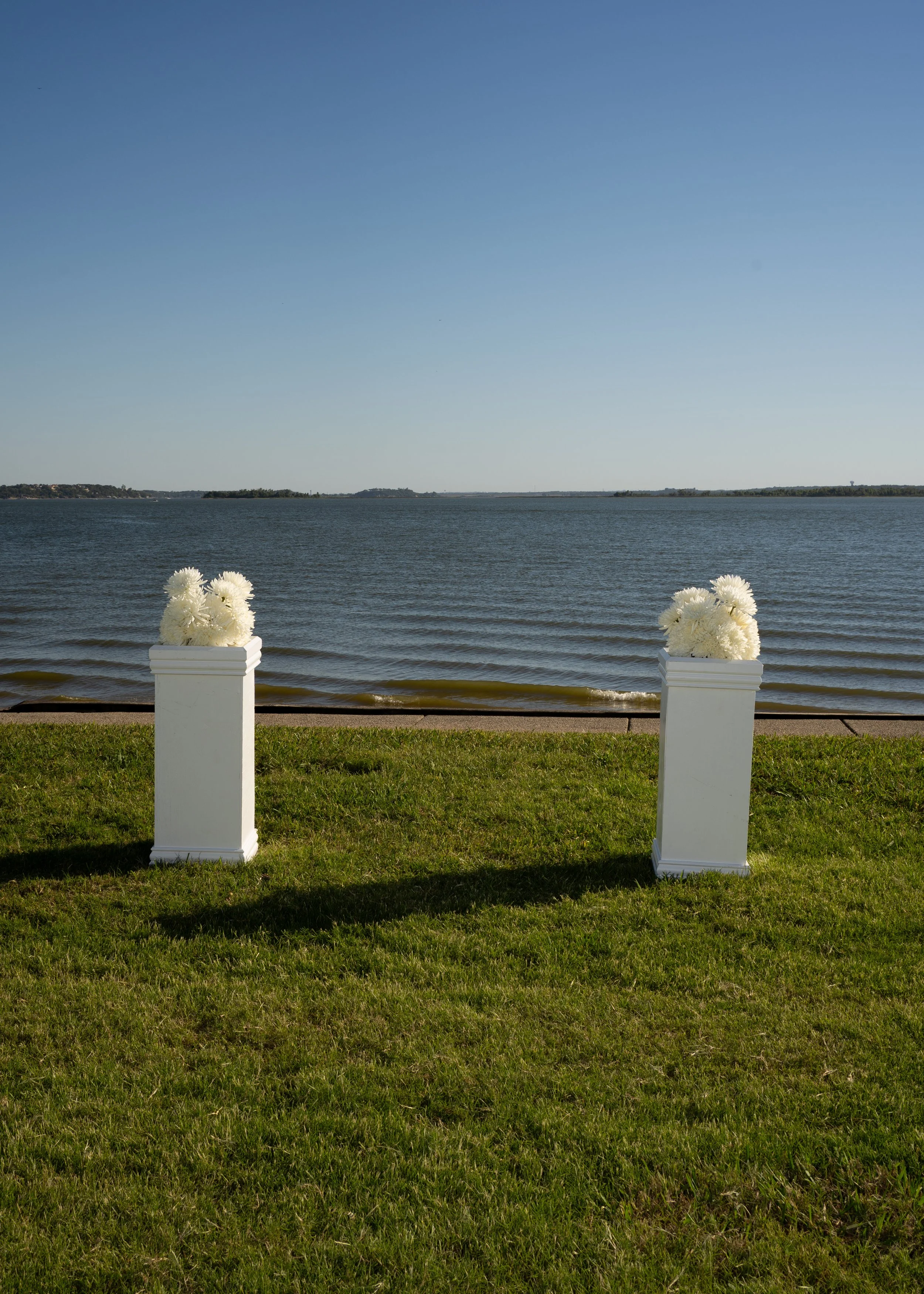Minimal ceremony setup with white chairs overlooking the water at a backyard wedding in Fort Worth, Texas.