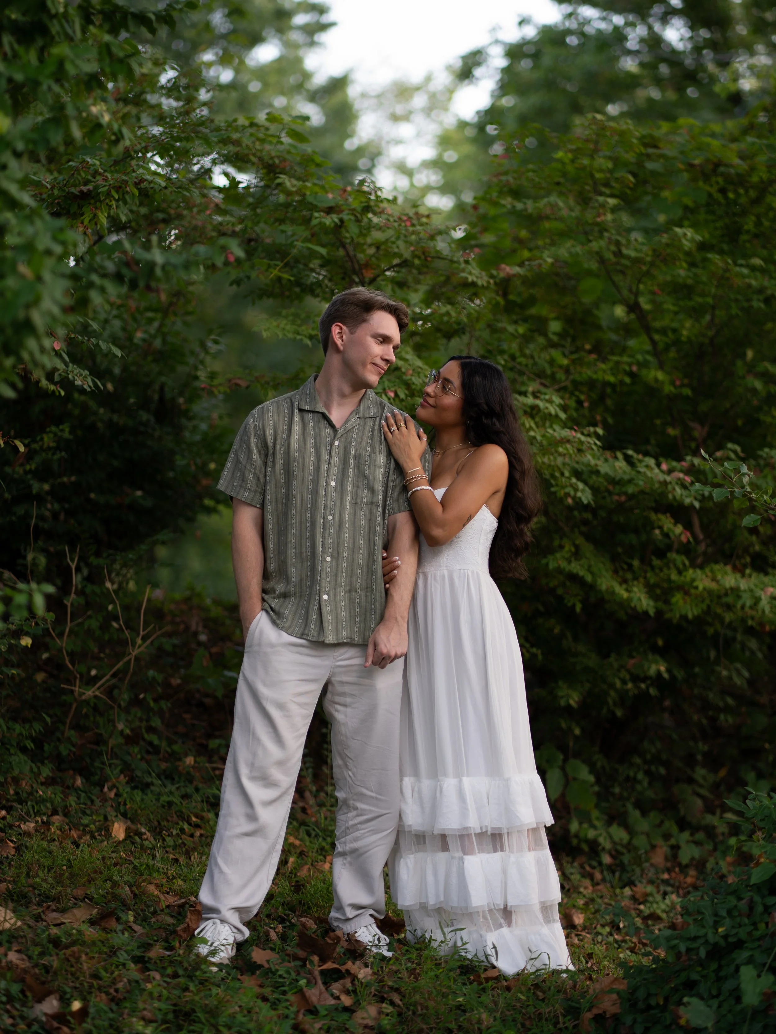 A relaxed and natural engagement portrait in Mammoth Springs, AR, framed by rich greenery and soft light.
