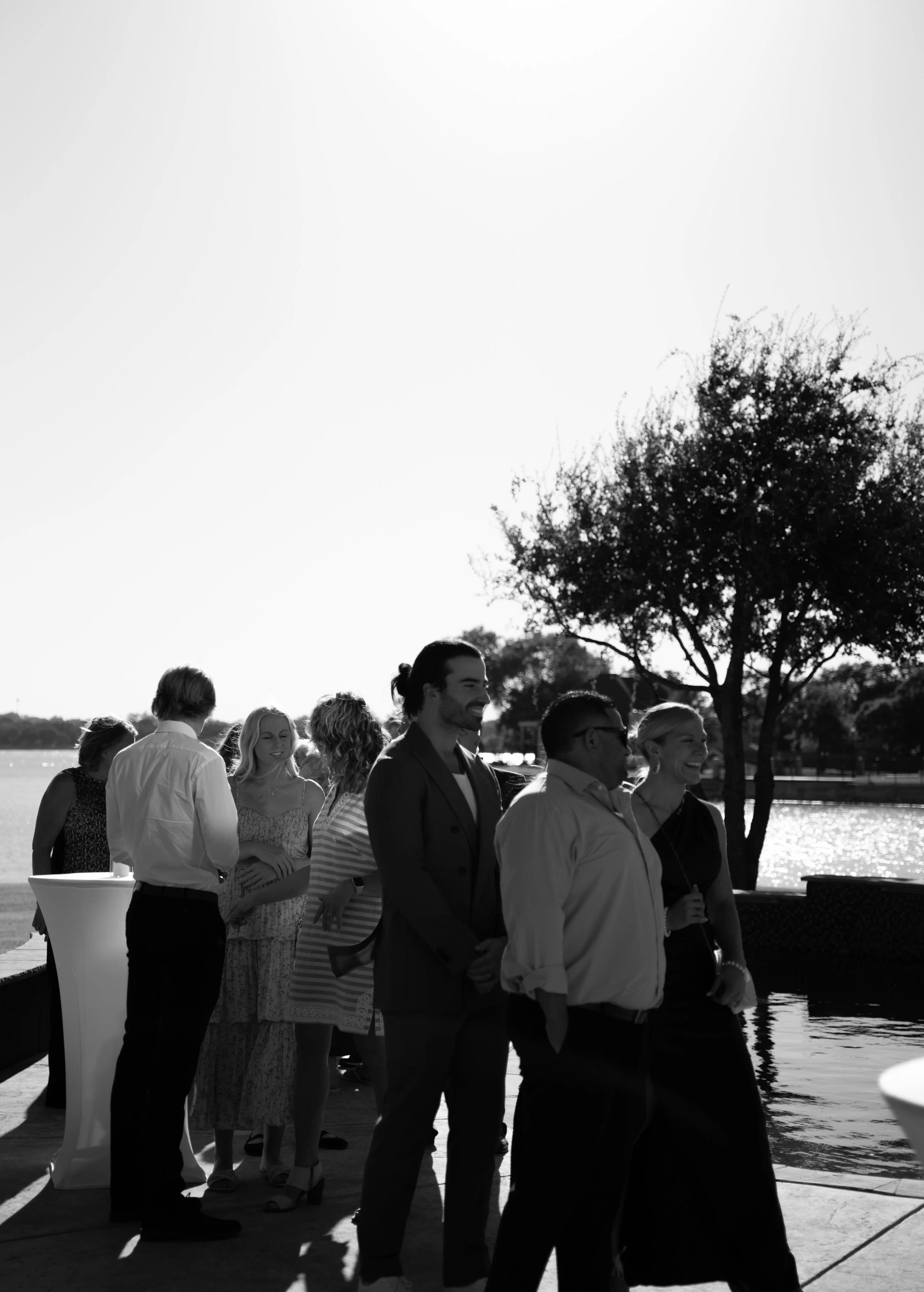 Candid guest interactions captured in black and white during a backyard wedding in Fort Worth, Texas.