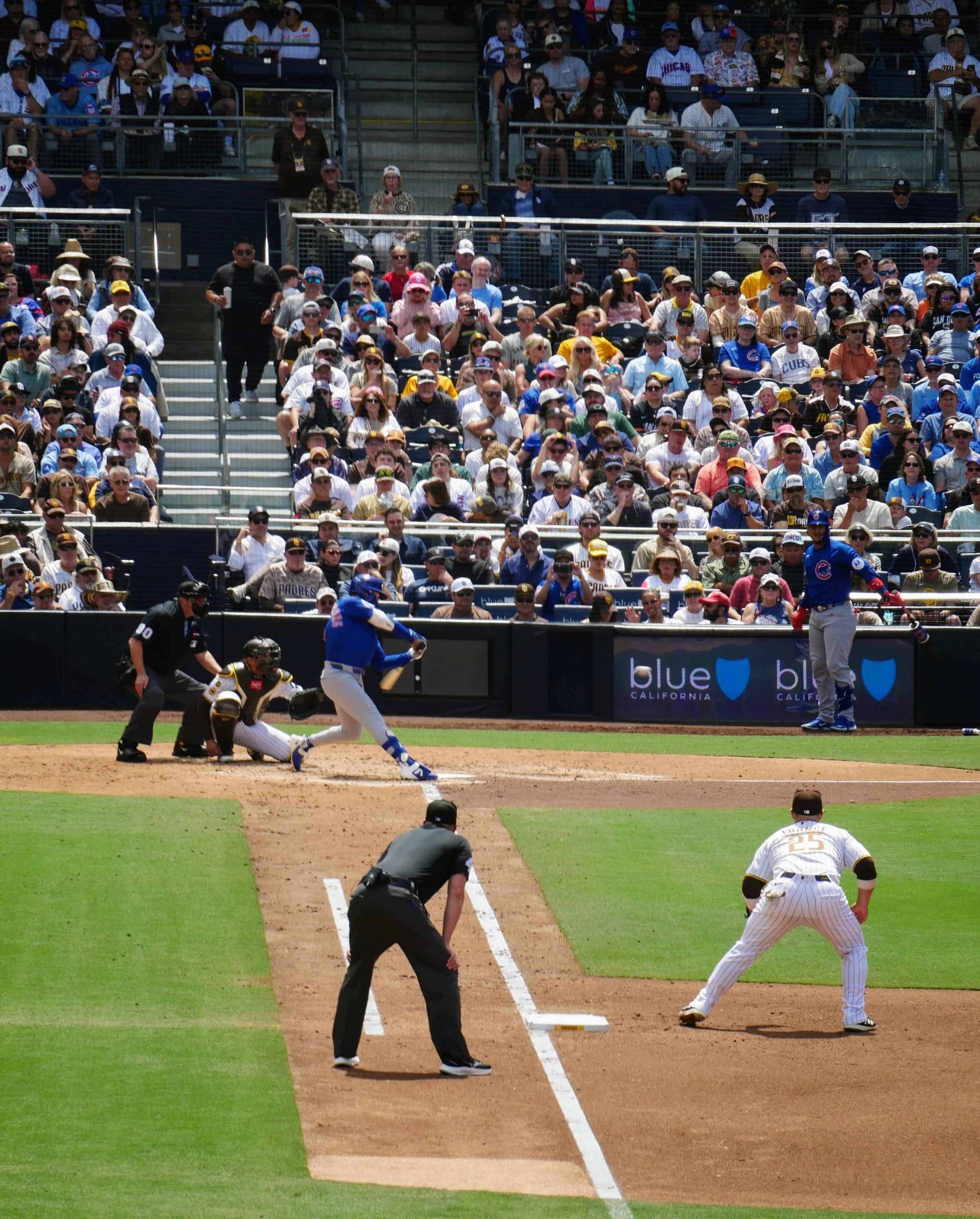 A baseball game in progress with a player at bat, a catcher, and an umpire near home plate, and spectators in the stands.