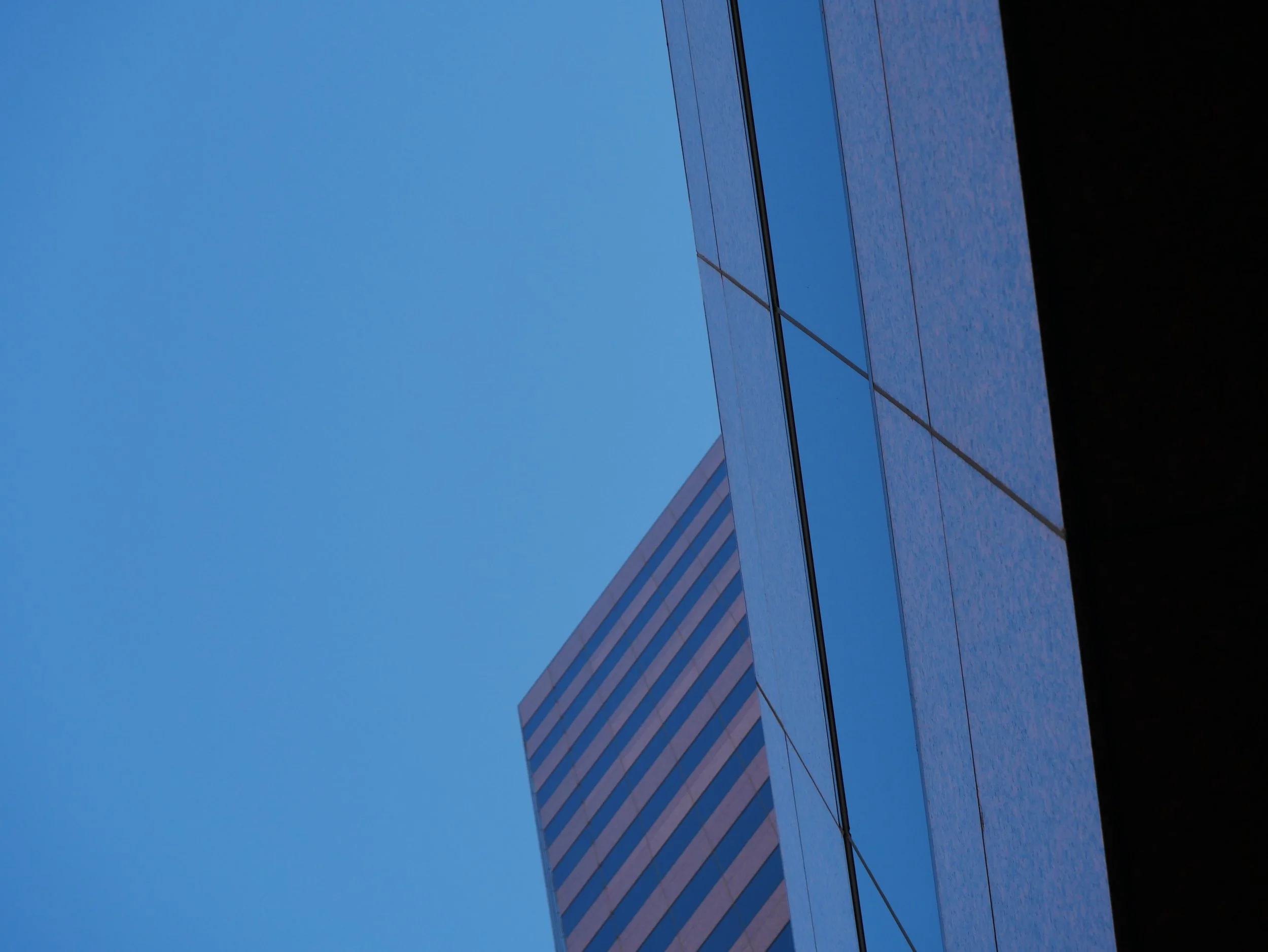 Close-up of a modern building with reflective glass windows against a clear blue sky.