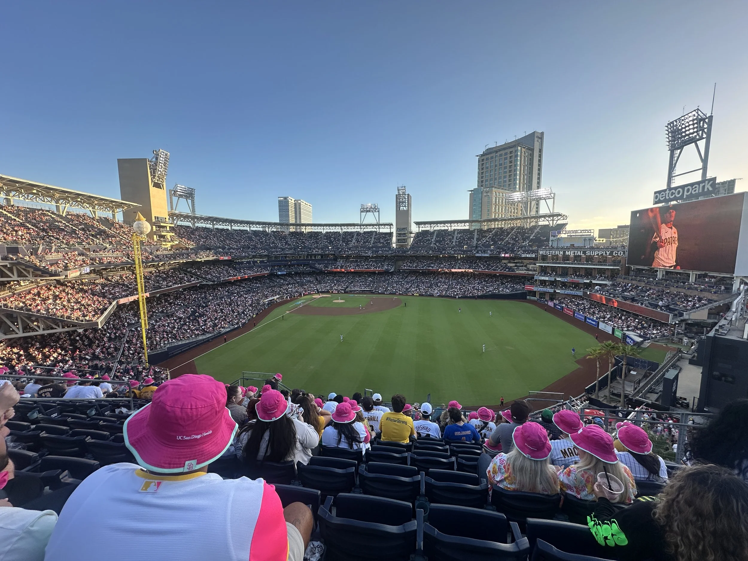 Baseball stadium filled with spectators, many wearing pink hats, during a game in Los Angeles.