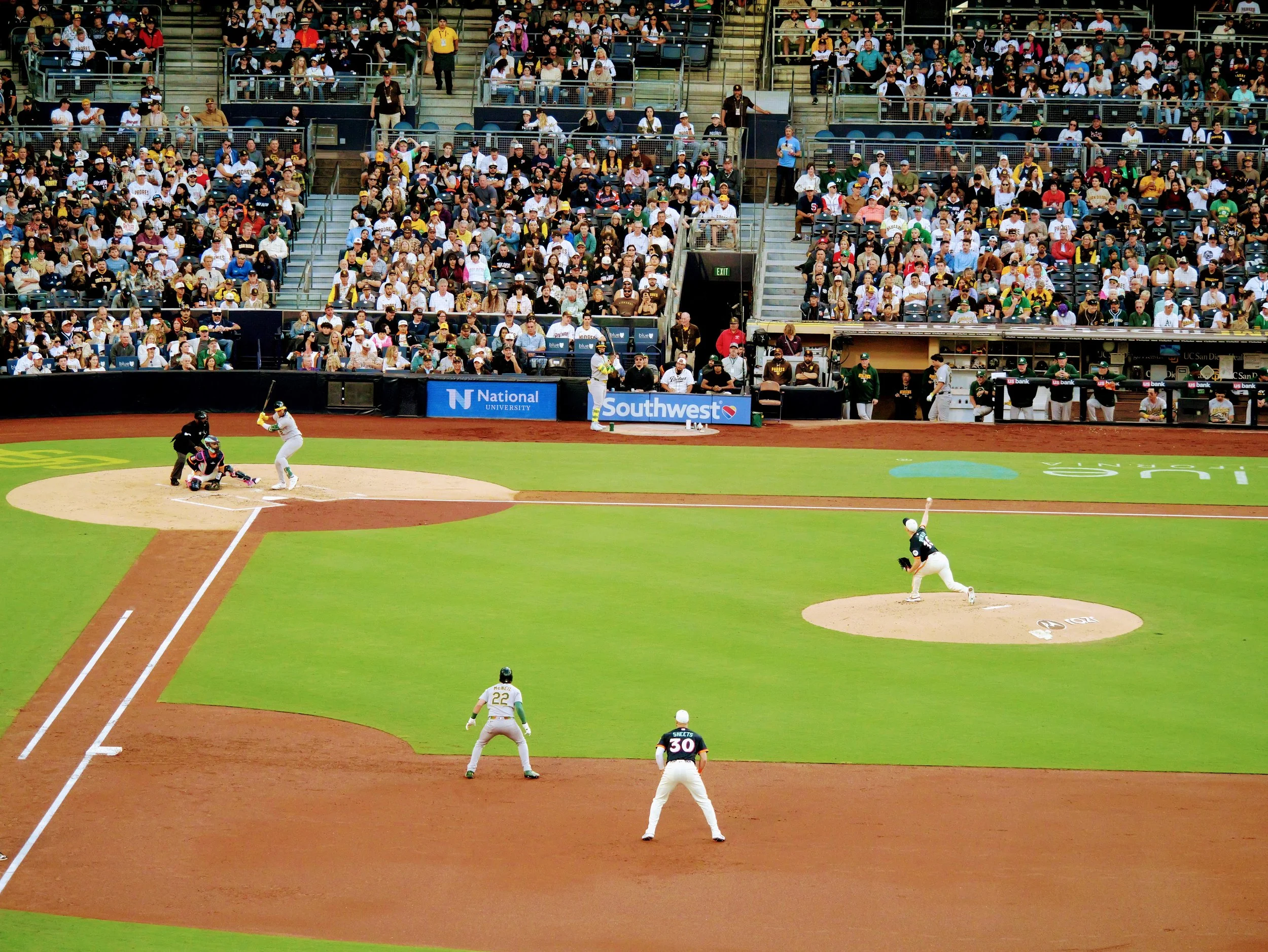 Baseball game in progress with players on the field and spectators in the stands.