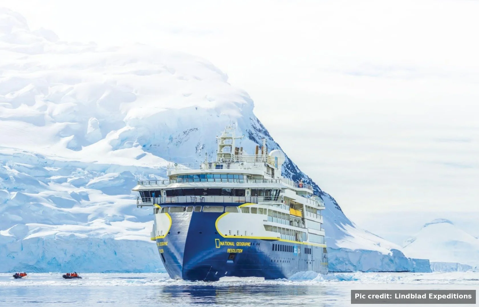 National Geographic Resolution expedition ship sailing past a massive iceberg in Antarctica