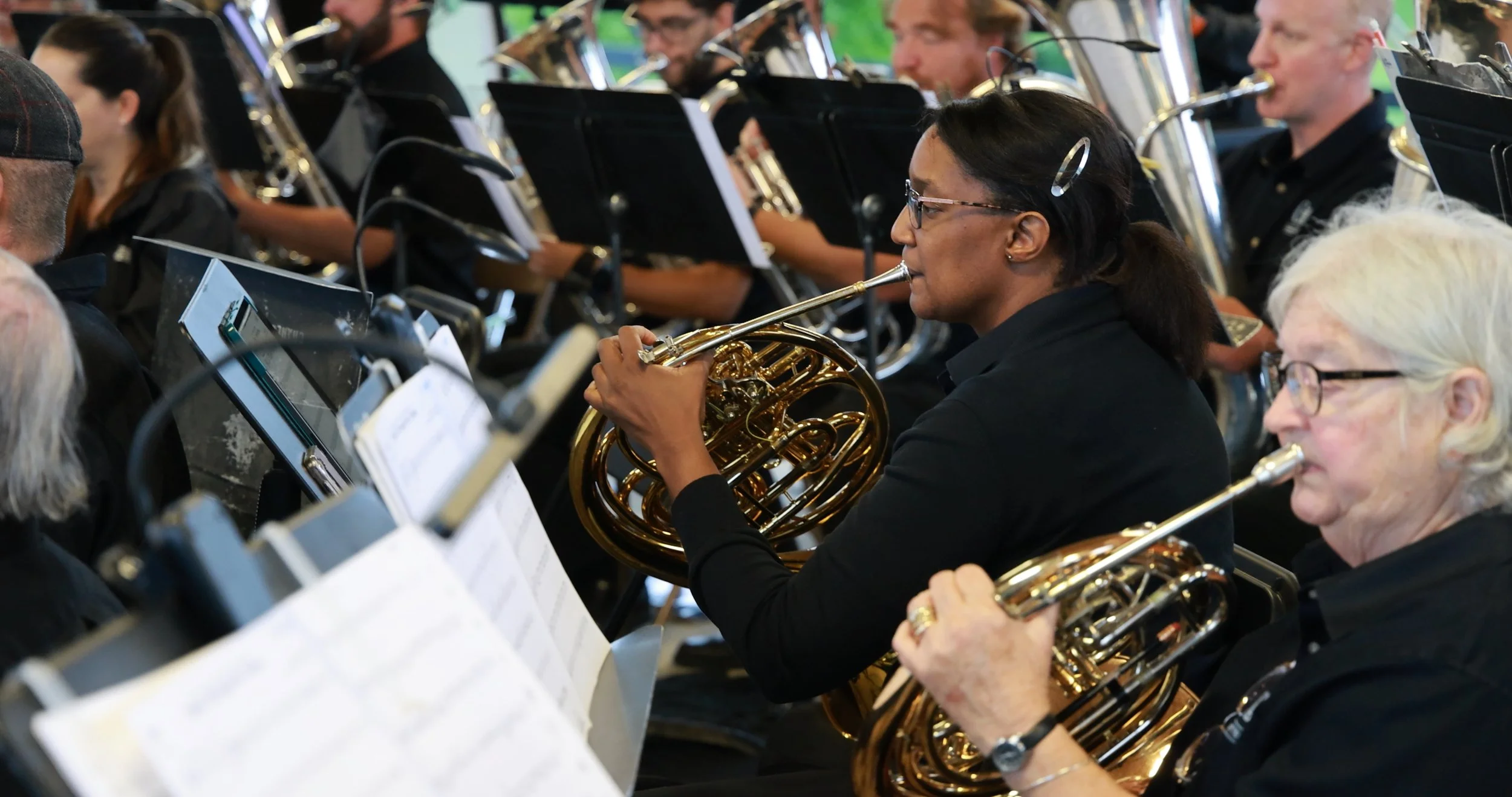 A group of musicians playing French horns and other wind instruments during an orchestra performance.