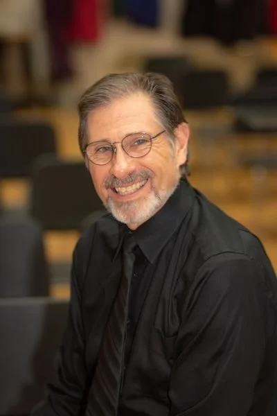 A man with glasses and a beard smiling at the camera