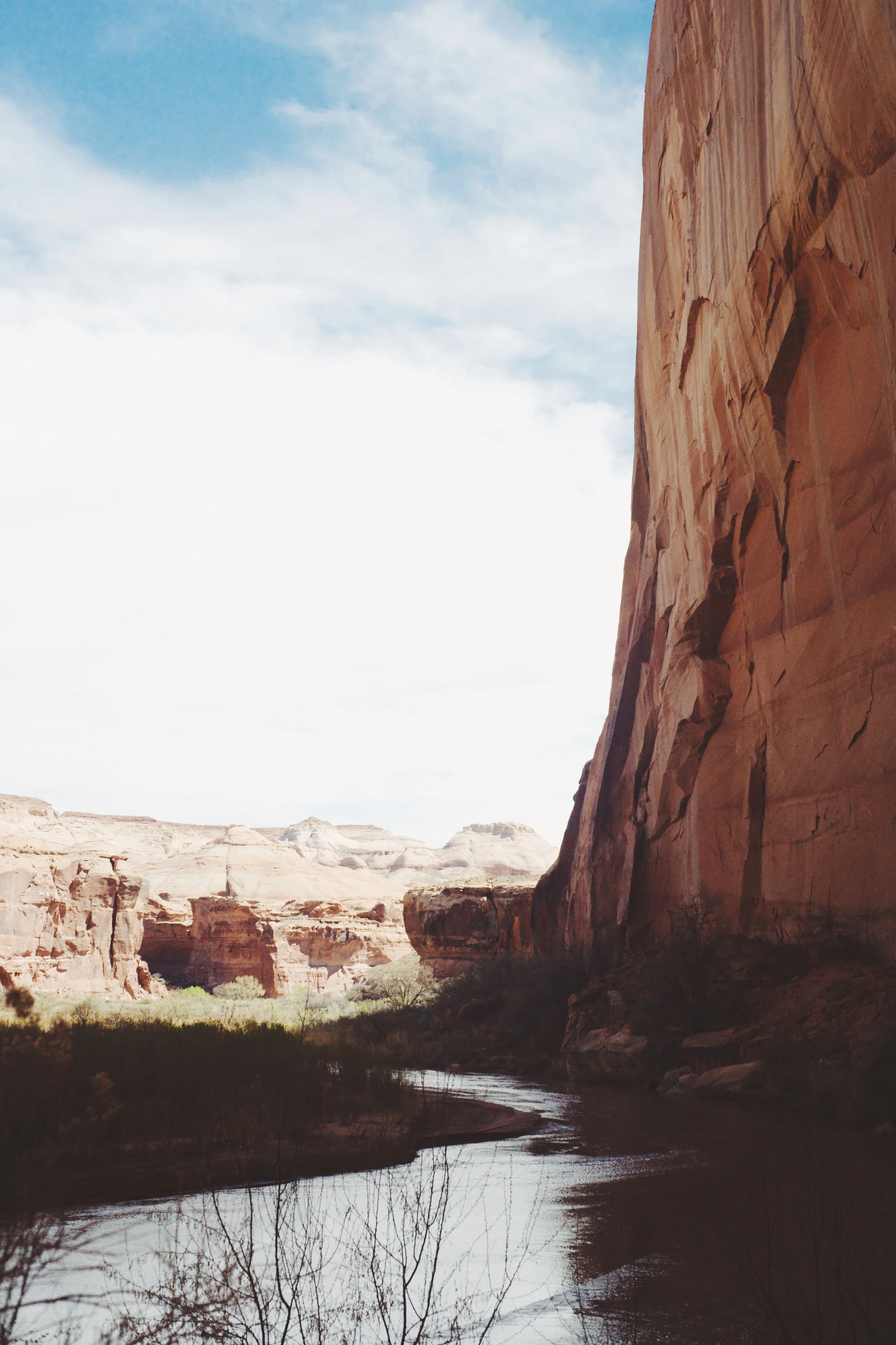 Scenic view of a canyon with towering rock formations and a river at the bottom, under a partly cloudy sky.