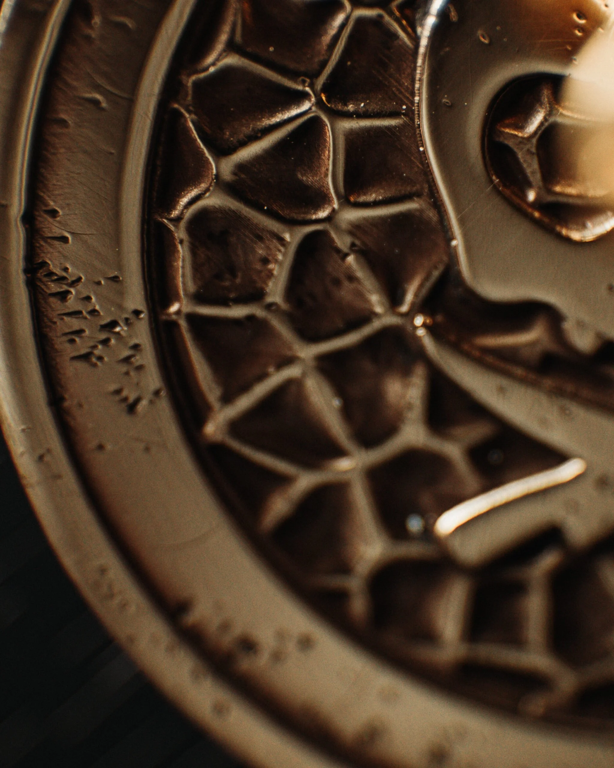 Close-up of a metallic surface with a honeycomb pattern and a circular edge, possibly part of a machine or tool.