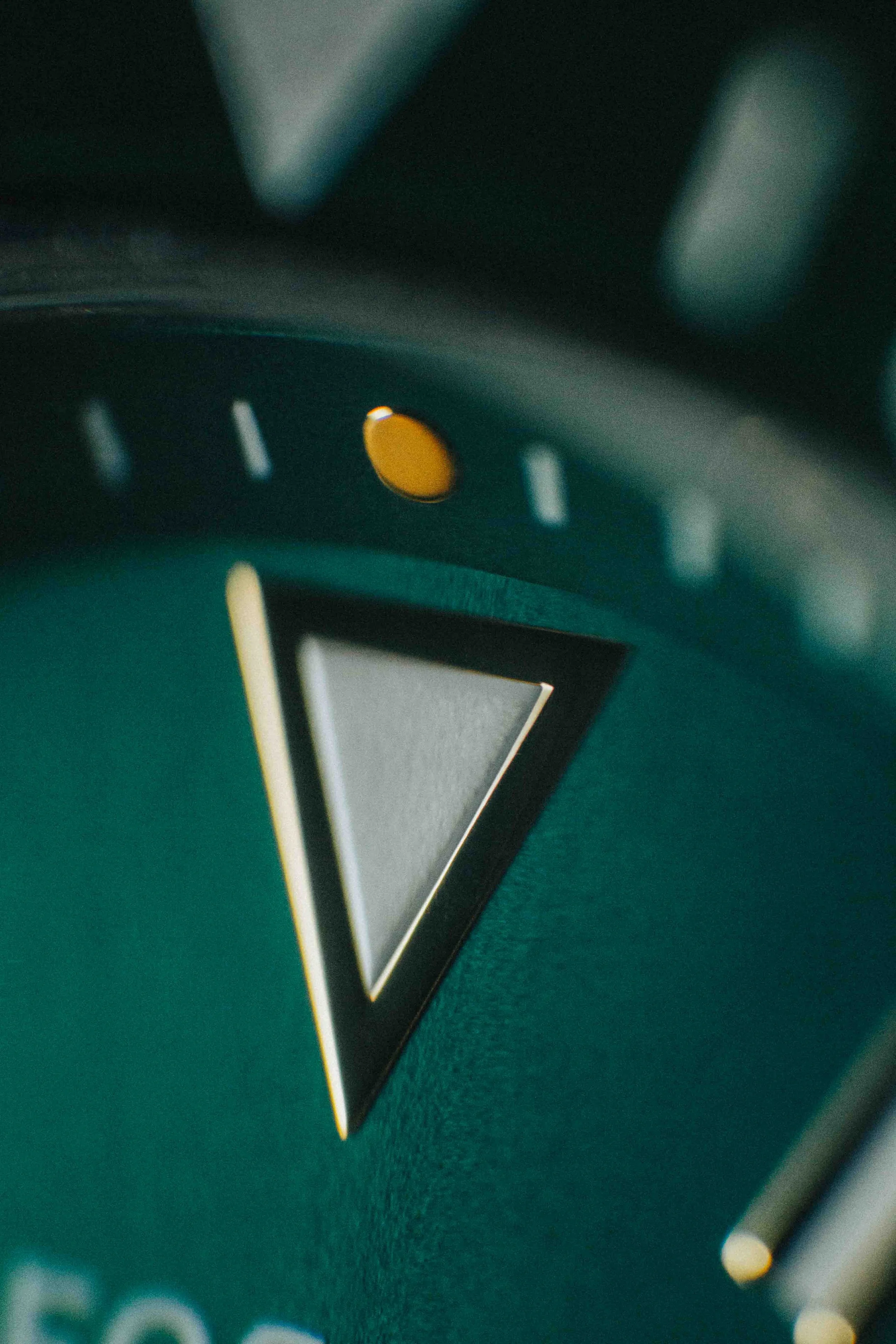 Close-up of a watch face showing the 12 o'clock position with yellow markers and a prominent triangular hour marker.