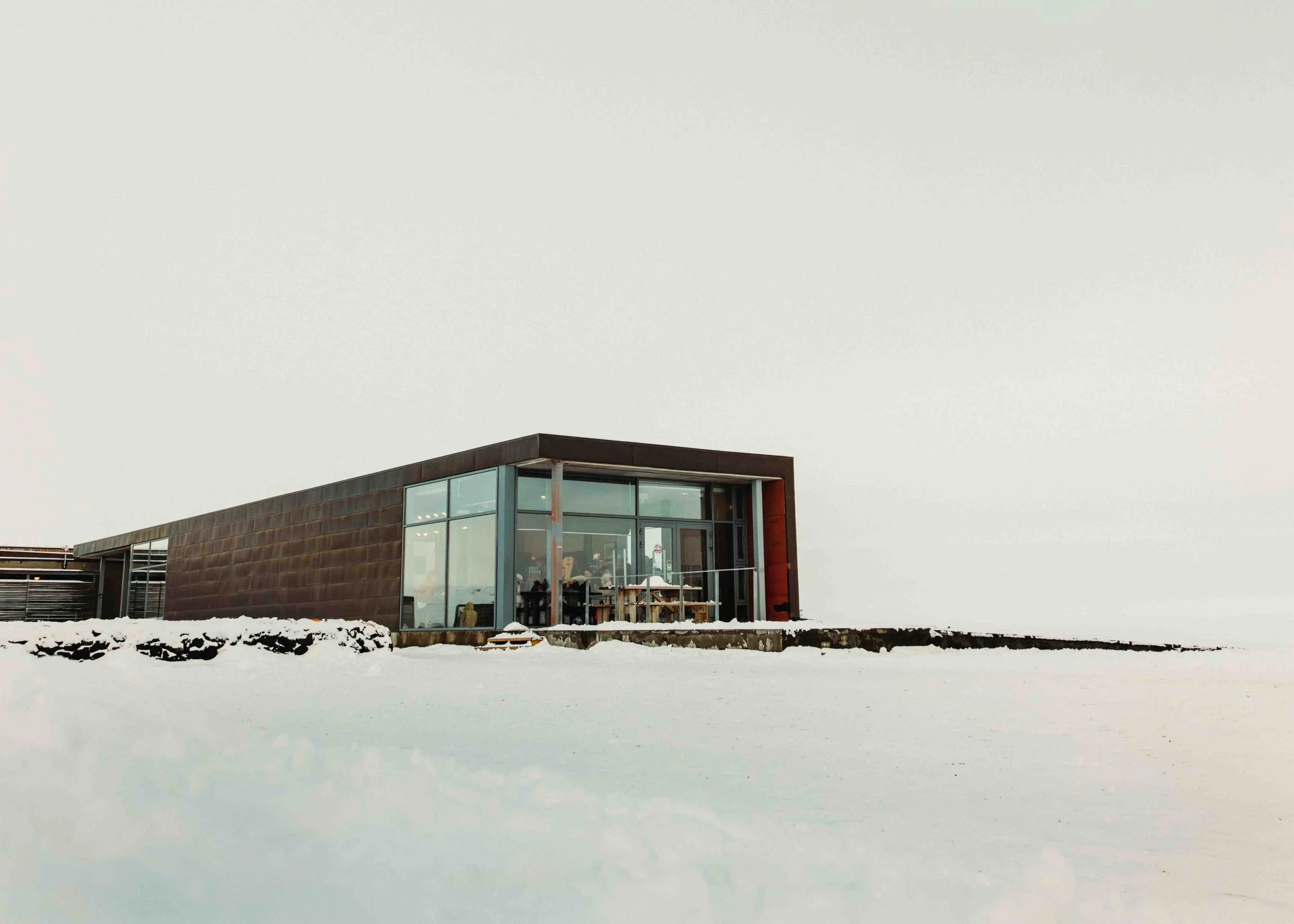 Modern building with large glass windows in a snowy landscape.