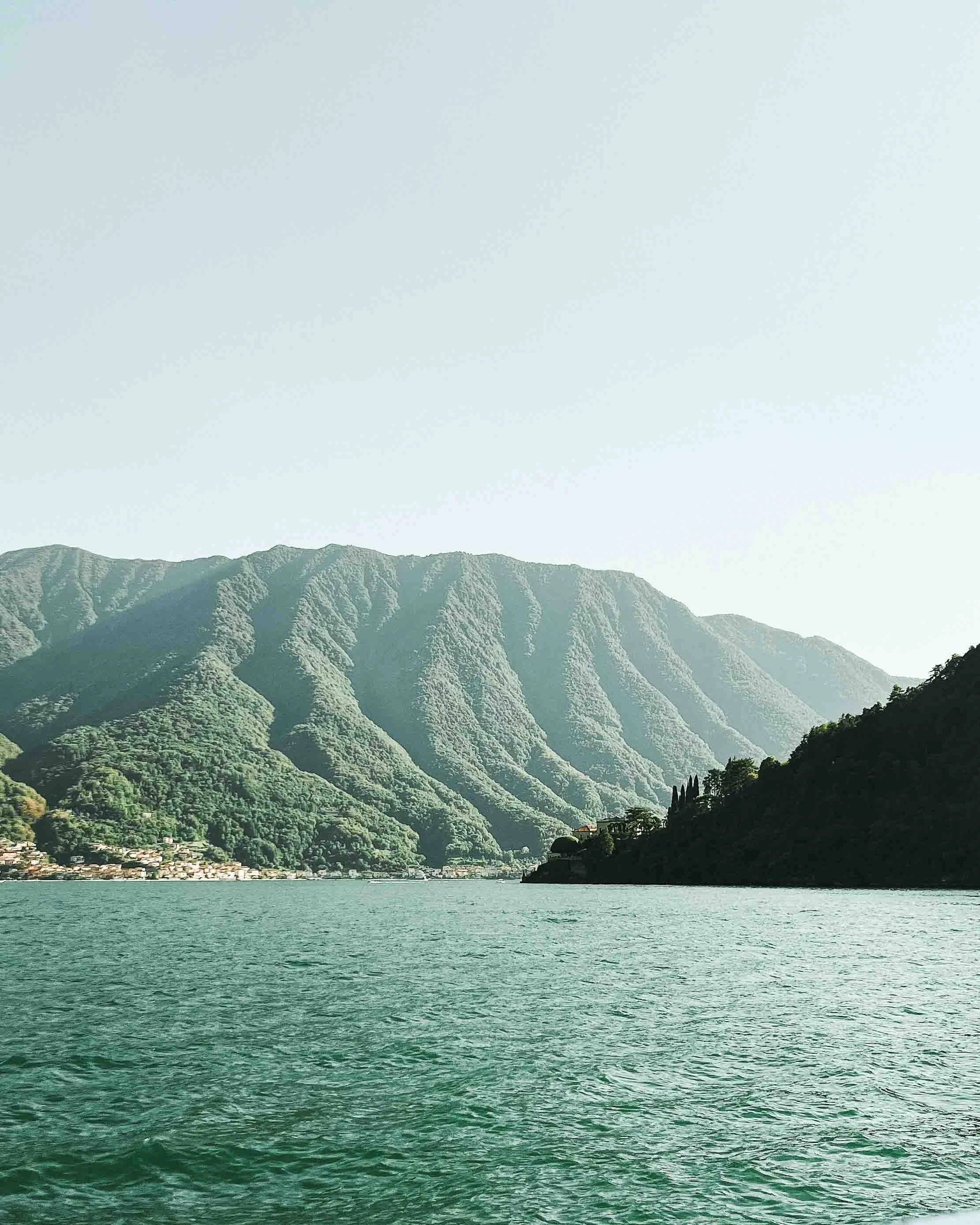 Scenic view of a lake surrounded by lush green mountains under a clear sky
