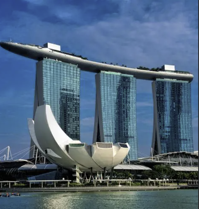 The Marina Bay Sands hotel in Singapore with its three tall glass towers and a boat-shaped rooftop structure connecting them, situated above a body of water.