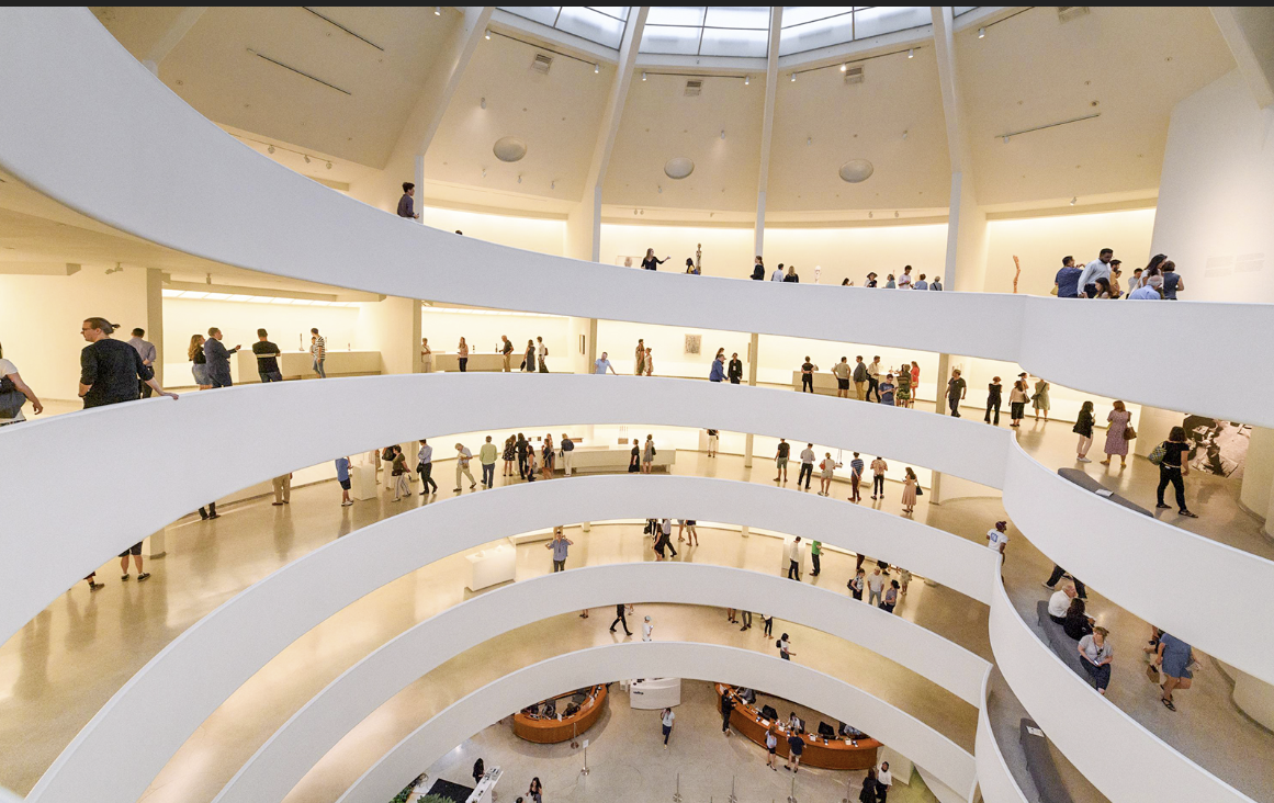 Interior of a modern art museum with multiple levels and visitors walking on the spiral ramps.