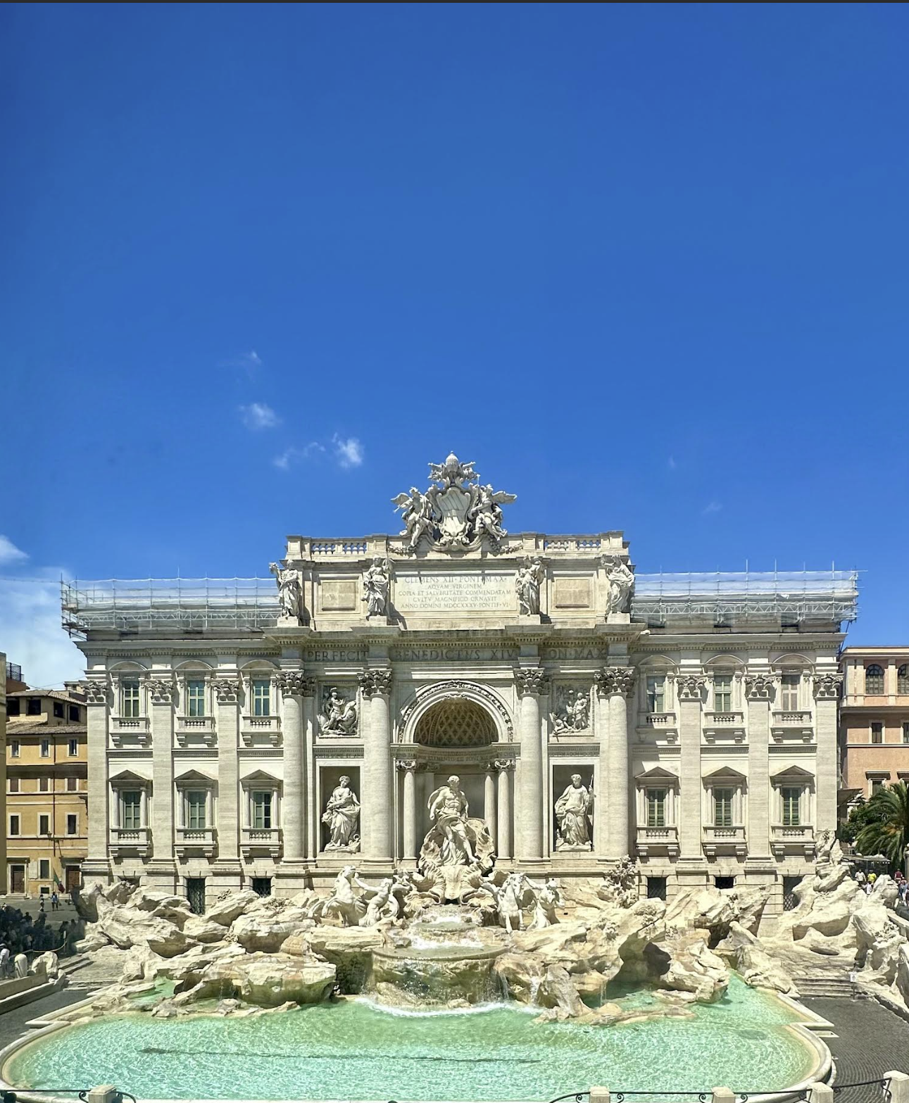 The Trevi Fountain in Rome, Italy, a large ornate Baroque fountain with statues and water features, under a clear blue sky.