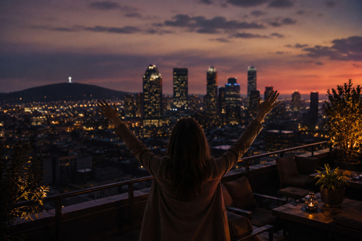 Une personne avec les bras levés, vue de dos, sur une terrasse avec vue sur la ville de Los Angeles au coucher du soleil.