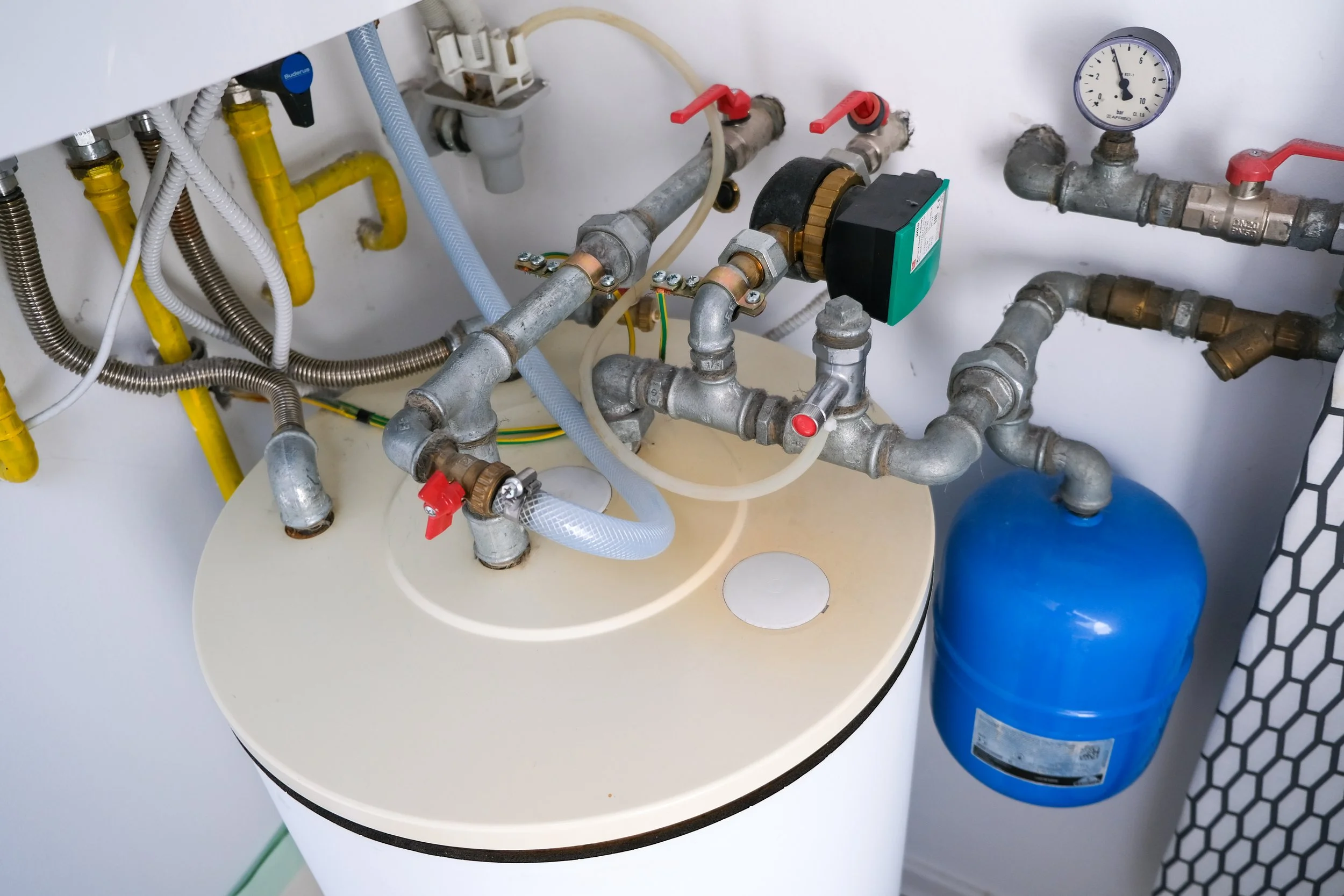 A water heater with pipes, gauges, and valves in a utility room.