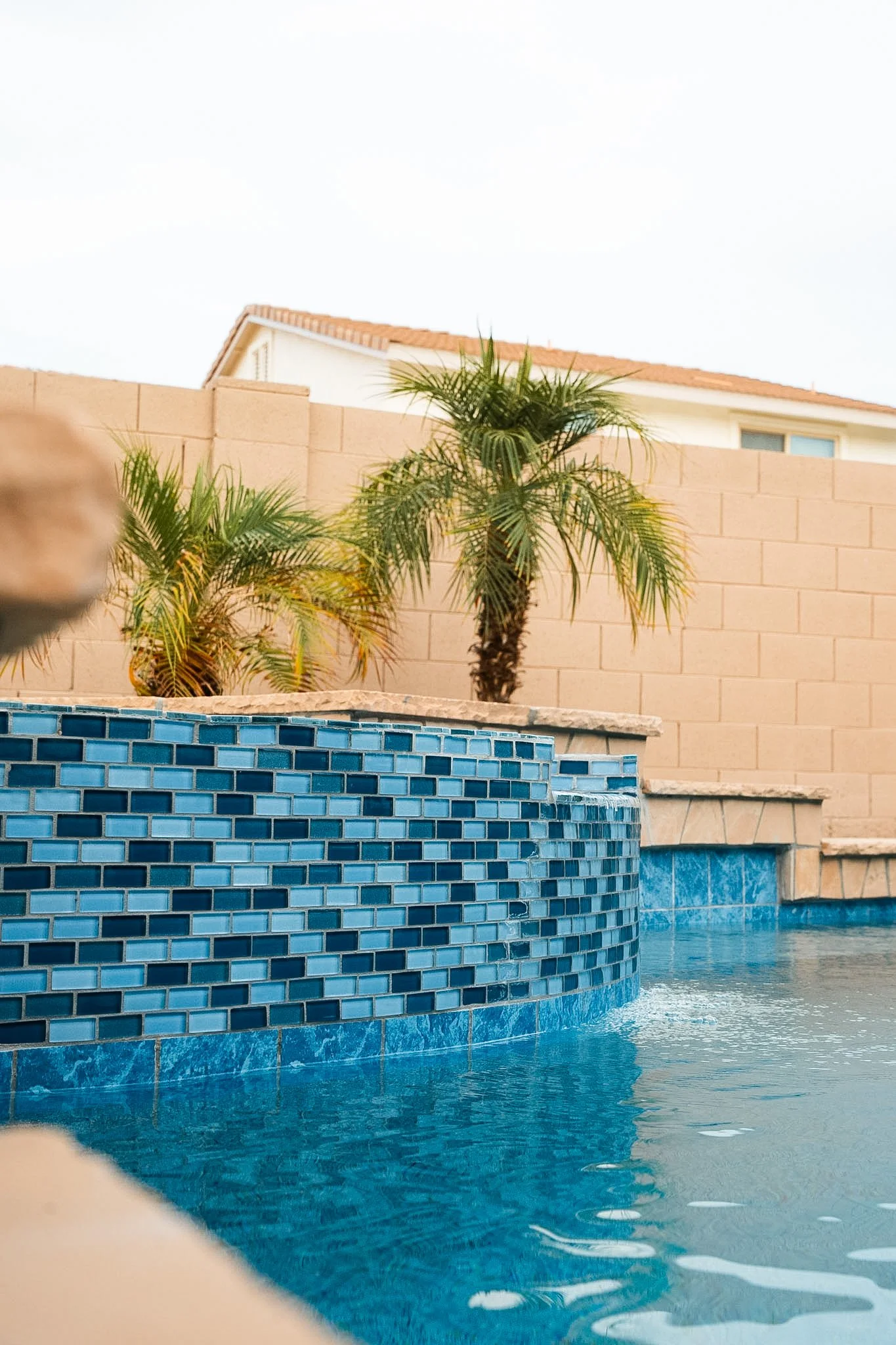 1" x 2" Glass tile on a spa spillover, paired with 6" x 6" Blue Seas Light Blue porcelain tile.