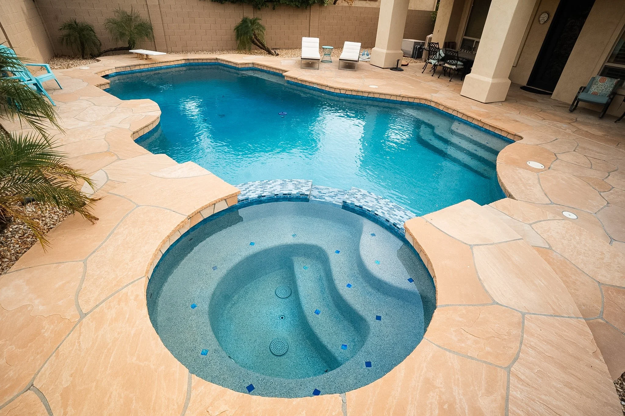 Remodeled swimming pool with Carribean blue mini pebble, 6" x 6" Blue Seas Light Blue porcelain tile, and 1" x 2" Orion Blue glass tile.
