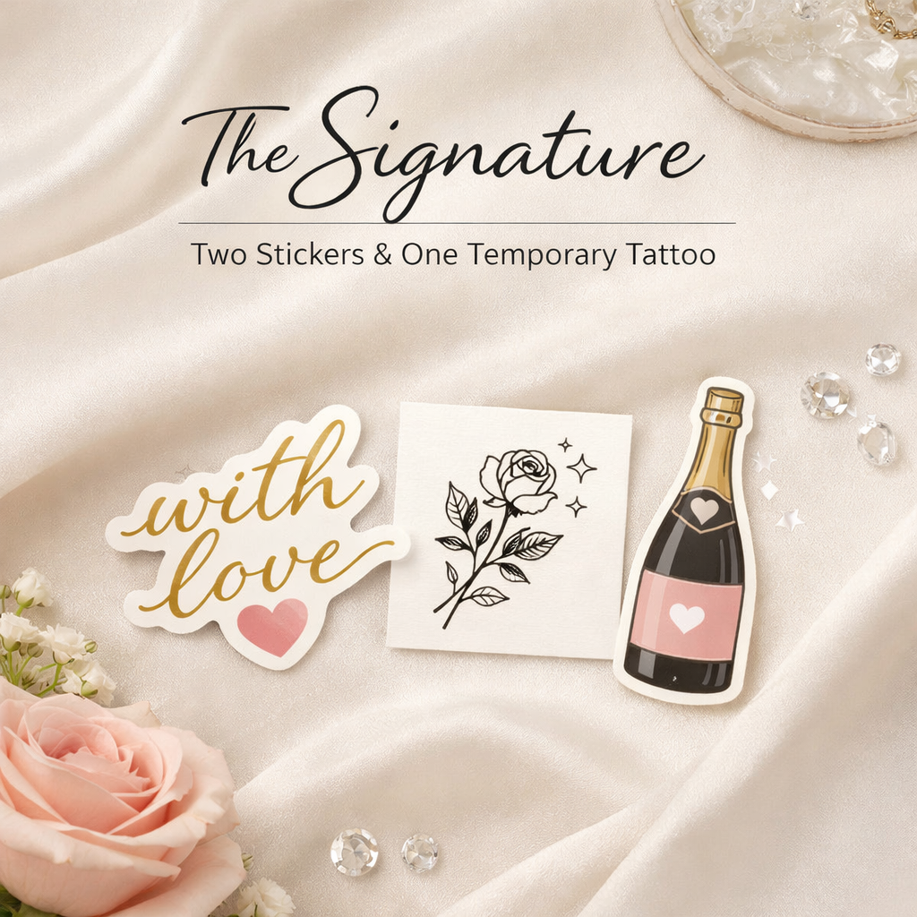 A decorative display featuring two sticker designs and one temporary tattoo, including a pink rose, clear rhinestones, a sticker saying 'with love' in gold script, a black-and-white rose drawing, and a champagne bottle sticker, all arranged on a silk