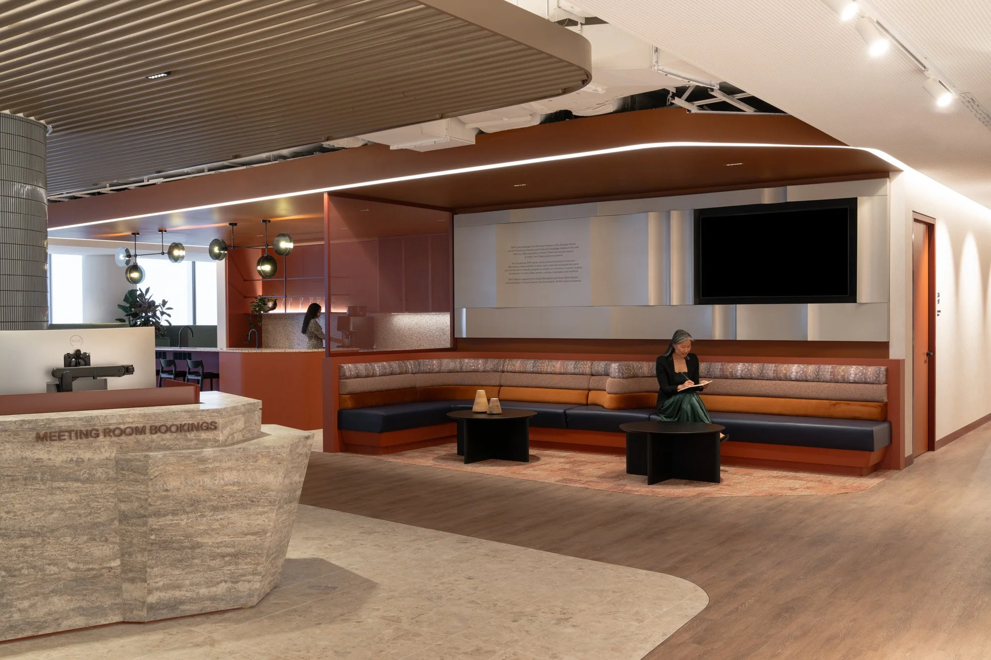 An open lobby space within BHP Perth offices. A large marble reception desk sits opposite printed banquette seating in earthy tones with navy blue accents.