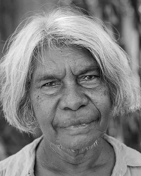 Black and white portrait of an Indigenous woman with a grey background.