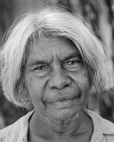 Black and white portrait of an Indigenous woman with a grey background.