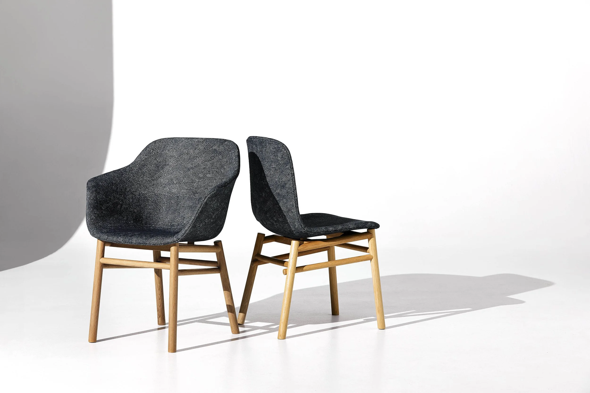 Two tub chairs with timber legs, upholstered in Willie Weston's Native Seeds 'Midnight' fabric featuring a delicate black and white pattern by Central Australian Aboriginal artist Jean Ngwarraye Long.