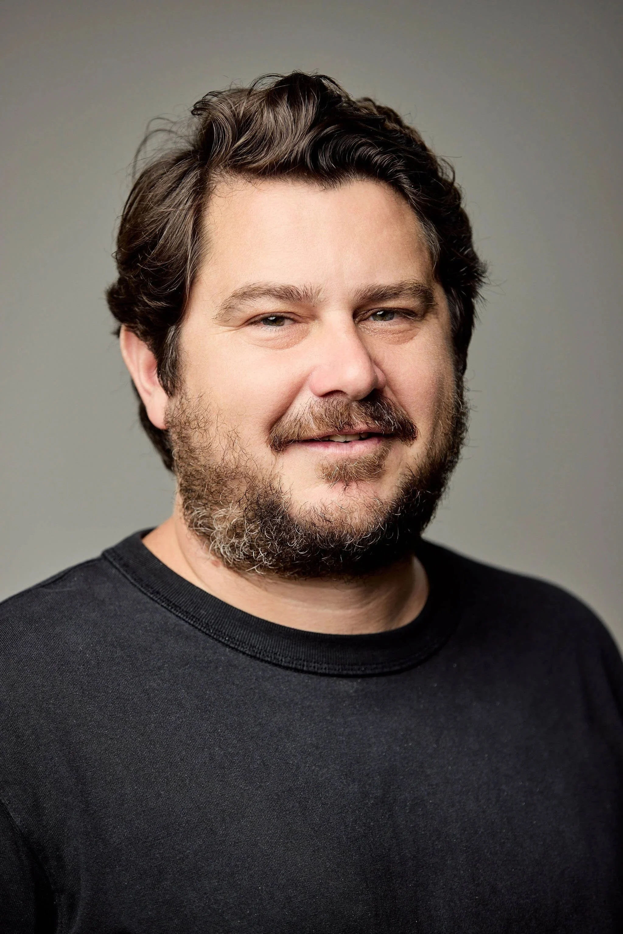 Portrait of a man with dark brown hair wearing a black t-shirt.