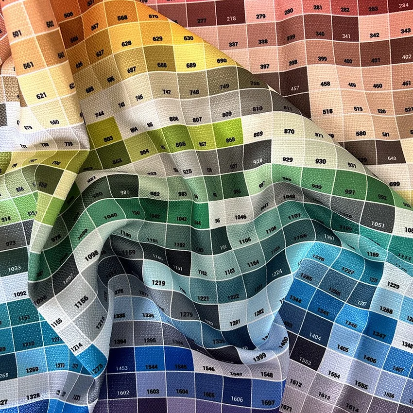 A close-up of a printed colour chart on fabric. Showing tones of yellows, greens, blues and peaches. Each coloured square has it's own code listed.