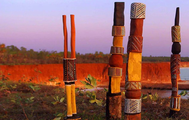 Pukumani poles sitting on a cliff top at sunset. They are carved and painted wooden mortuary poles created by the Tiwi people of Bathurst and Melville Islands.