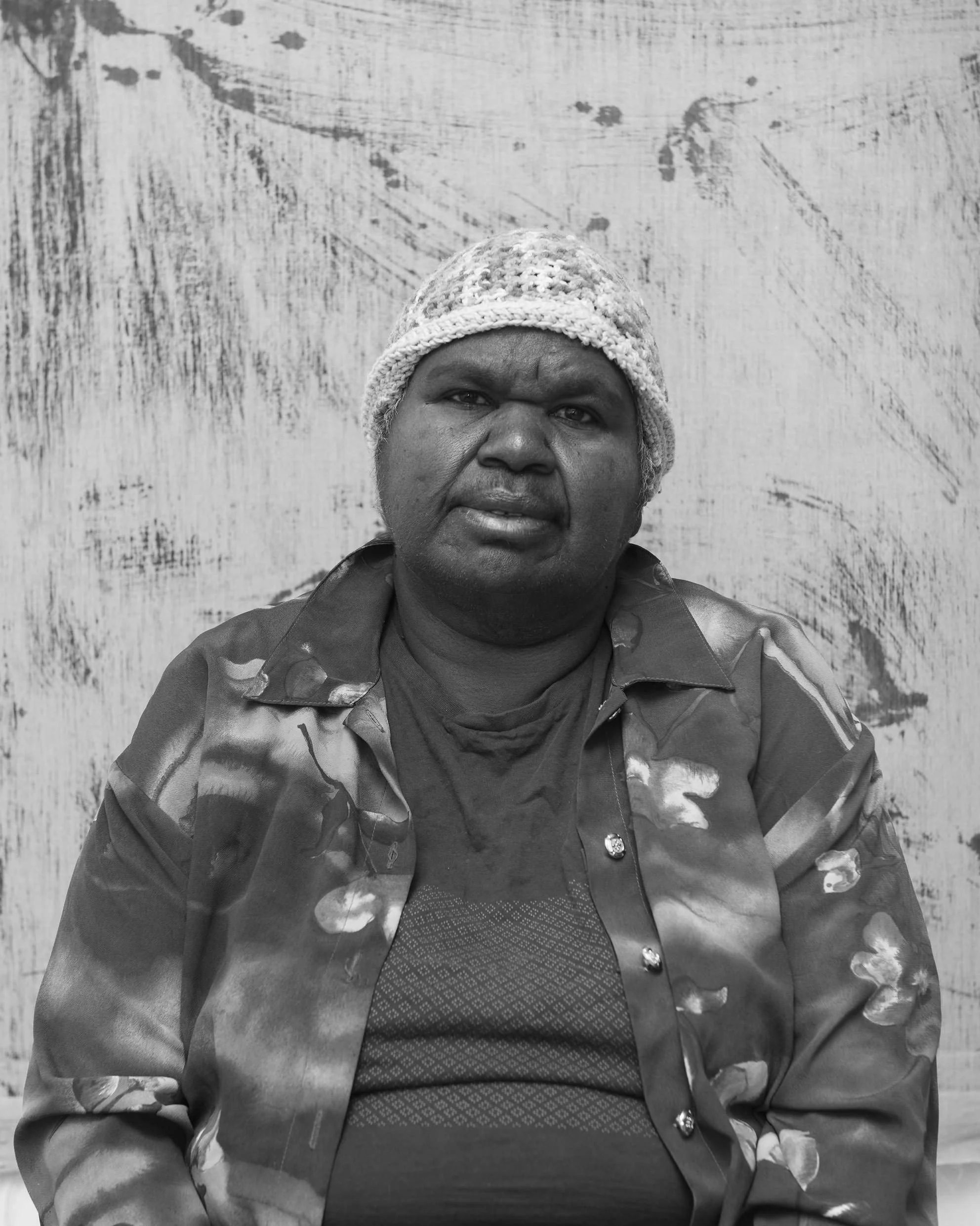 Black and white portrait of Indigenous woman with painted background.