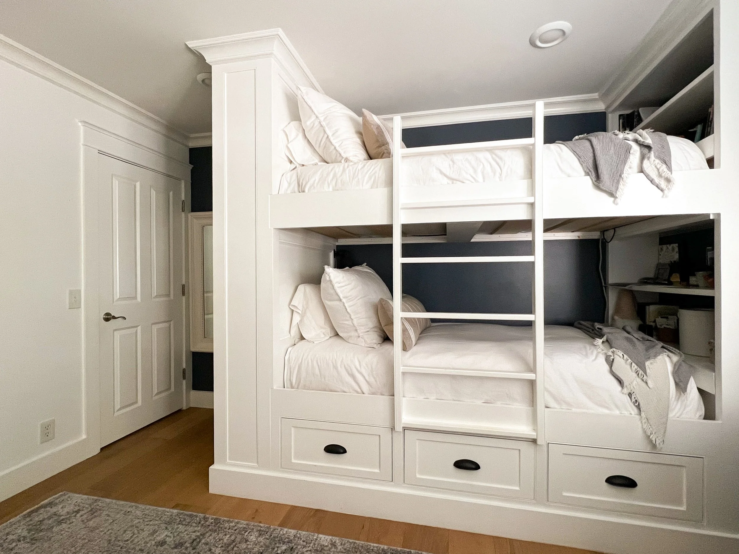 Built in bunk beds created private spaces filled with storage and display shelves for two teenage girls who had to share a room.  The custom built in created more floor space, making this small bedroom feel more spacious and airy.