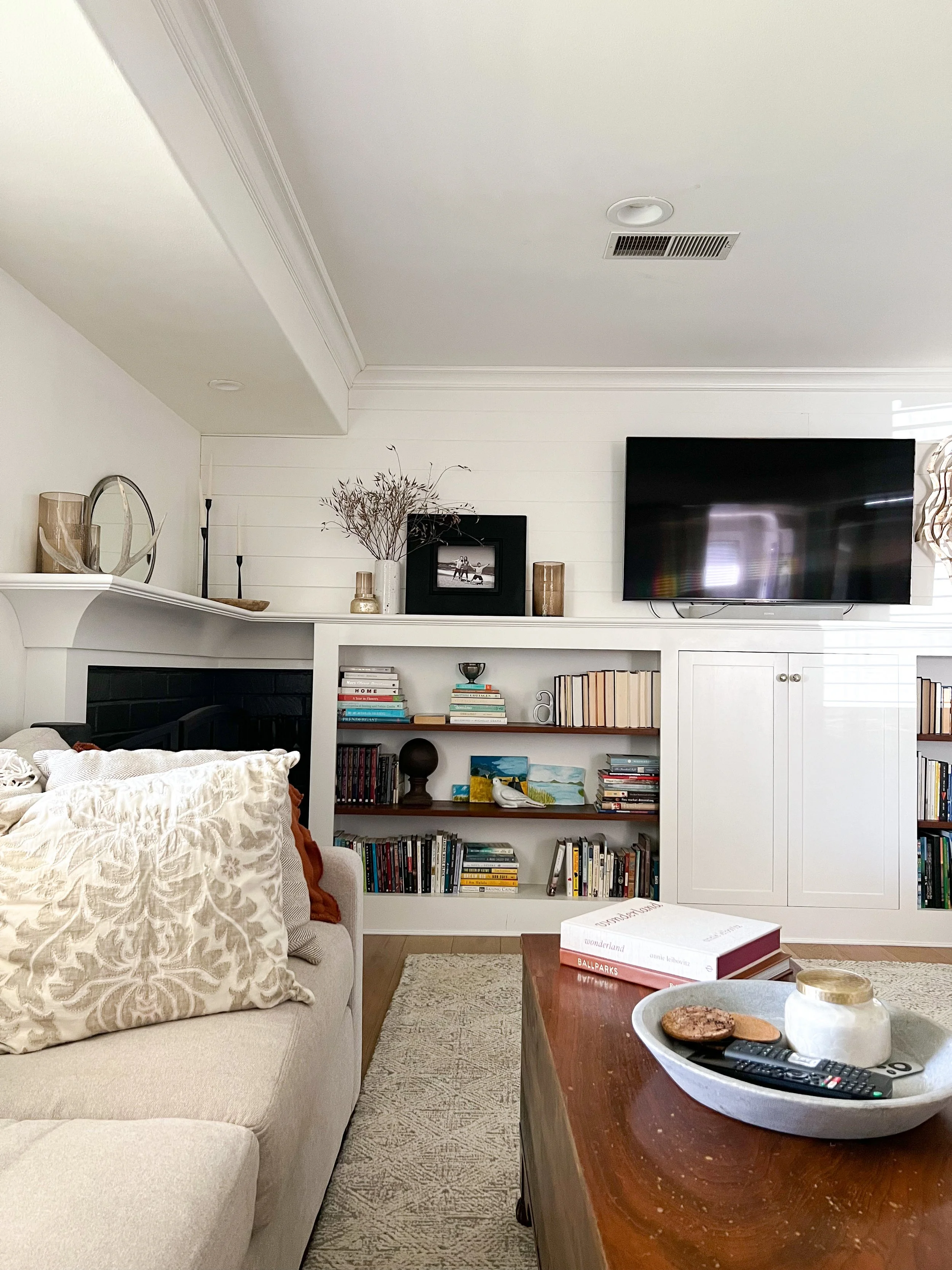This living room was lacking attractive storage and needed to feel a little more spacious.  The updated mantle, open shelving and closed cabinet space delivered a connected design style that was attractive and functional.