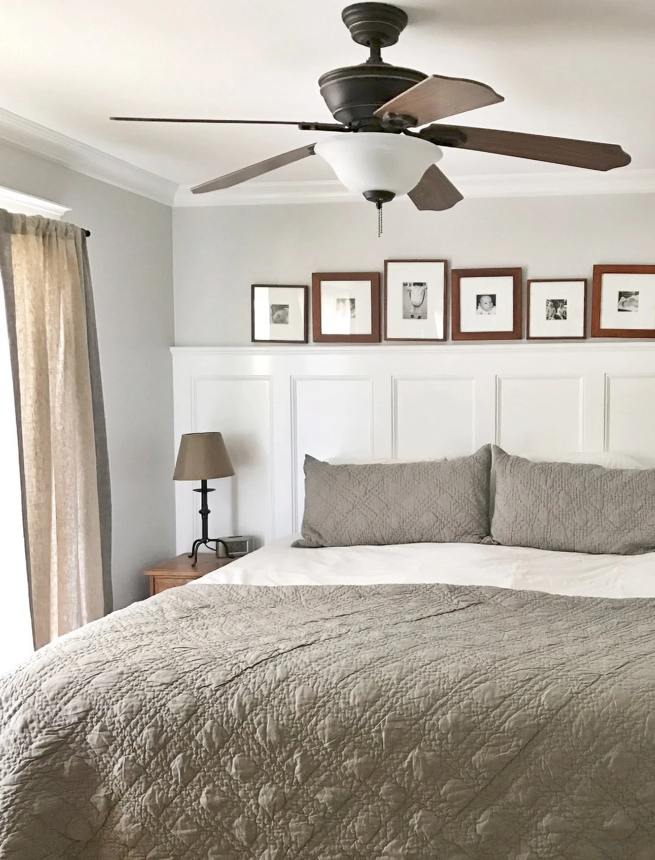 Wainscoting was added to this bedroom as an alternative to a headboard.  Displaying framed photos across it expanded the space between the walls, and using light paint colors helped to illuminate the room.