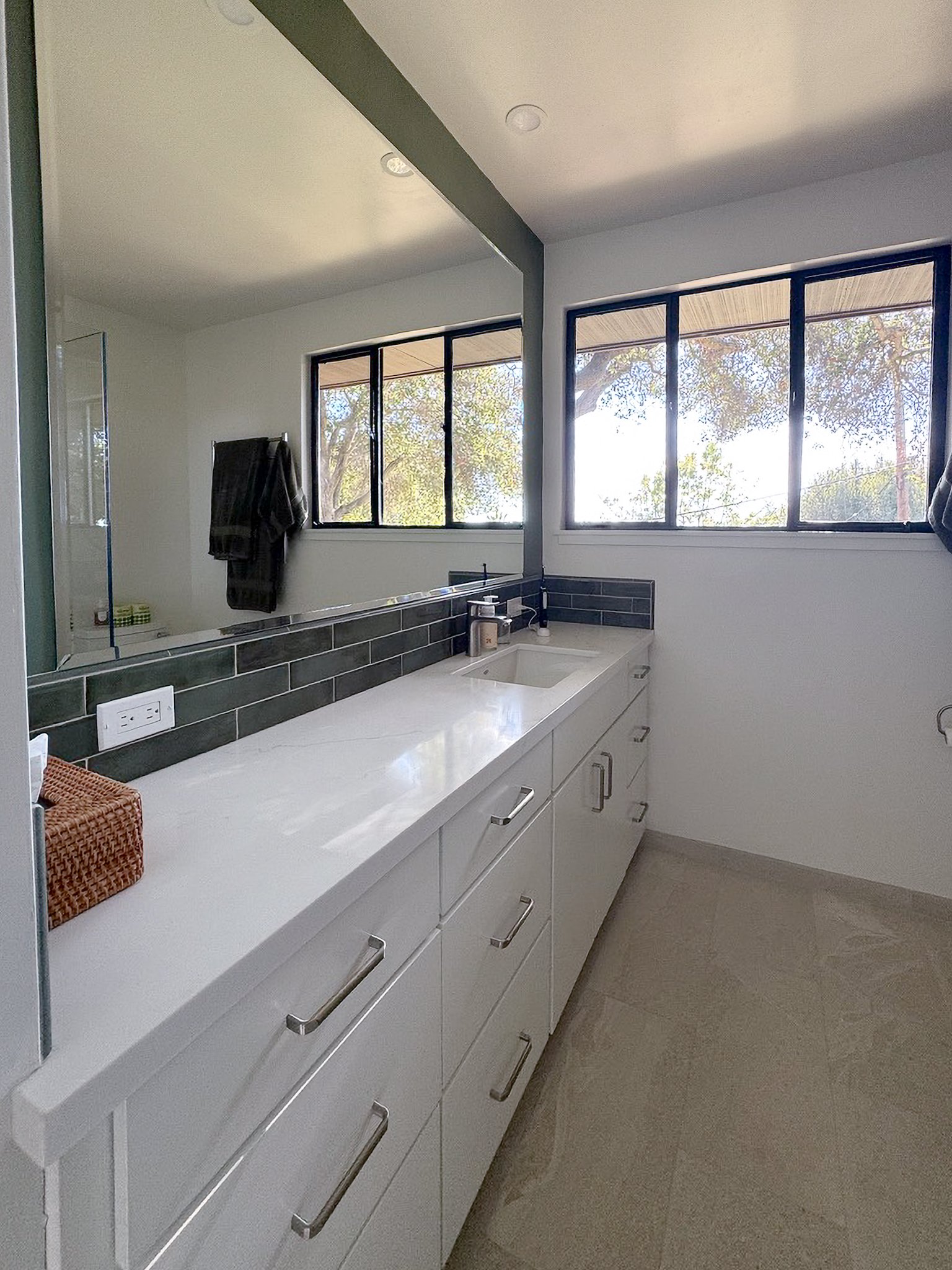The fresh updated tile, backsplash, countertop, and vanity create an inviting space to get ready in the morning.  The simplicity in design gives the small space a feeling of being larger and more open.  Added storage and the towel warmer add function