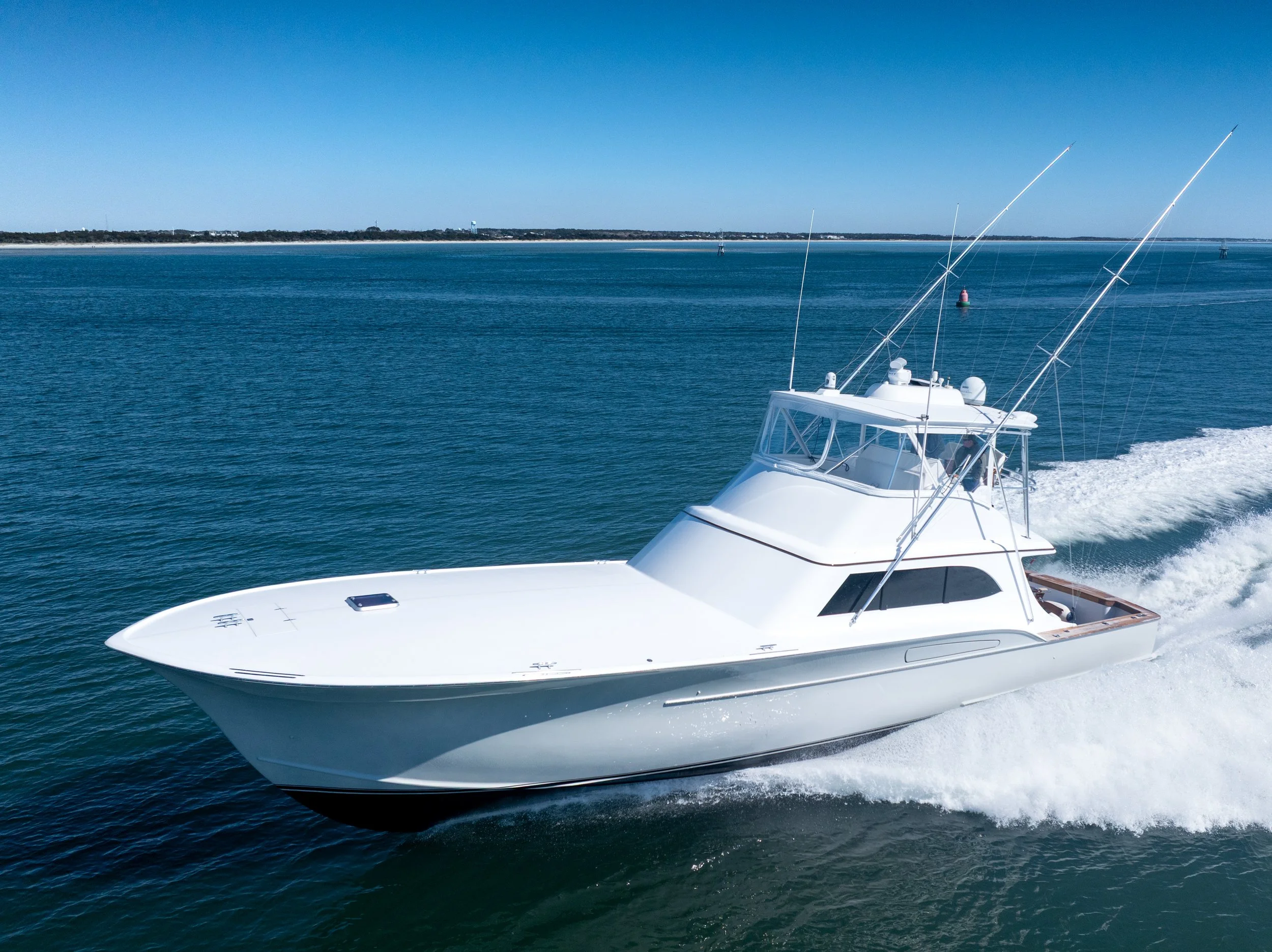sport fishing yacht cruising on blue water with a clear sky and distant shoreline