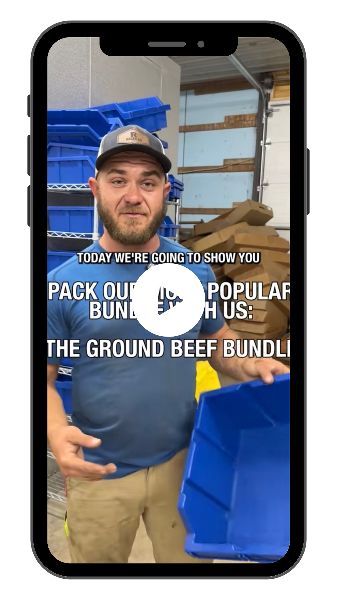A man with a beard and cap shows a blue plastic container inside a storage area or warehouse with shelves and stacked cardboard pieces. Overlaid text on the image reads: "Today we're going to show you pack our most popular bundle with us: the ground beef bundle."