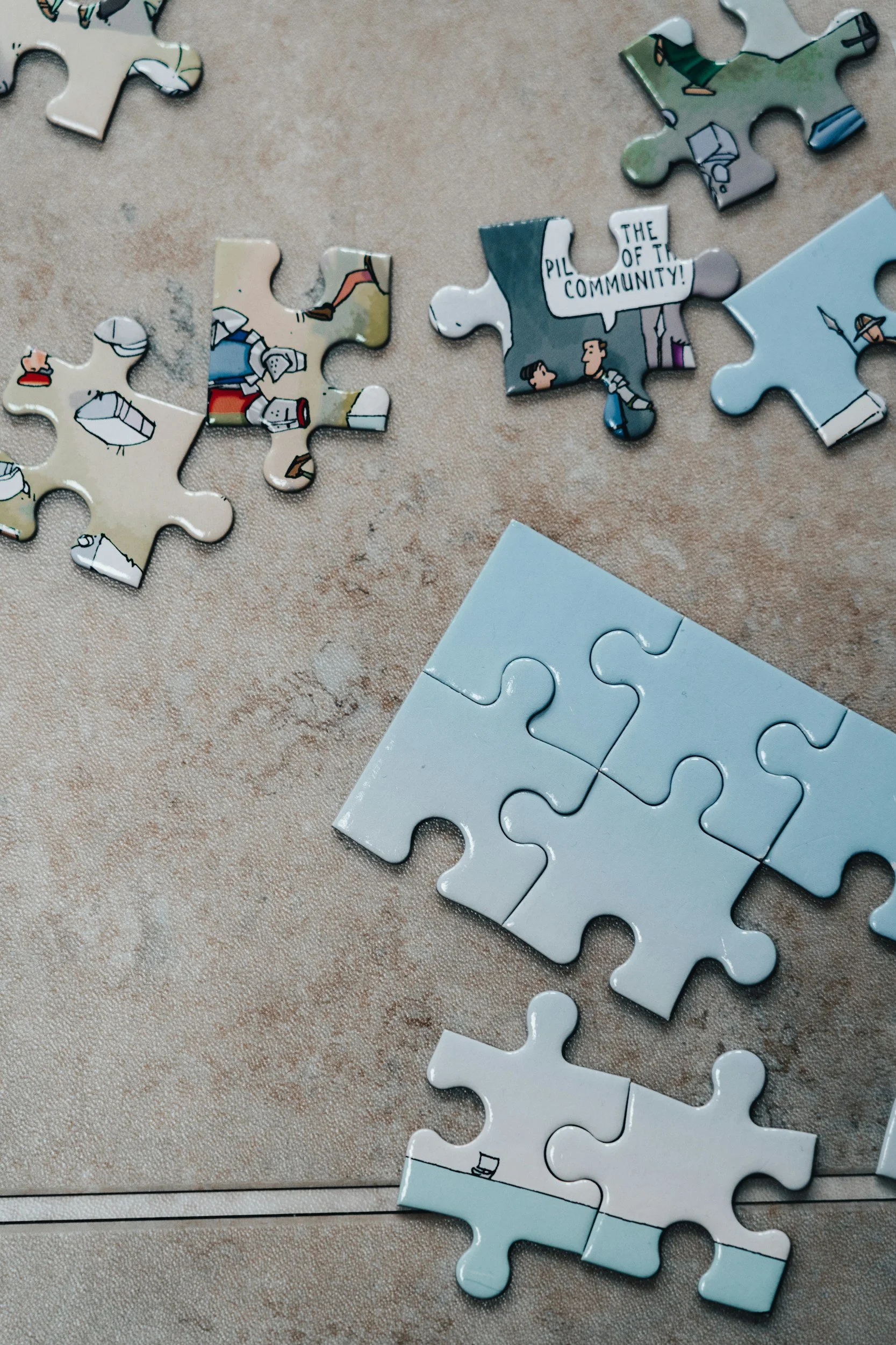 Photo of partially assembled puzzle pieces on a table, with one puzzle piece featuring a comic-style speech bubble that says 'The of the community!'