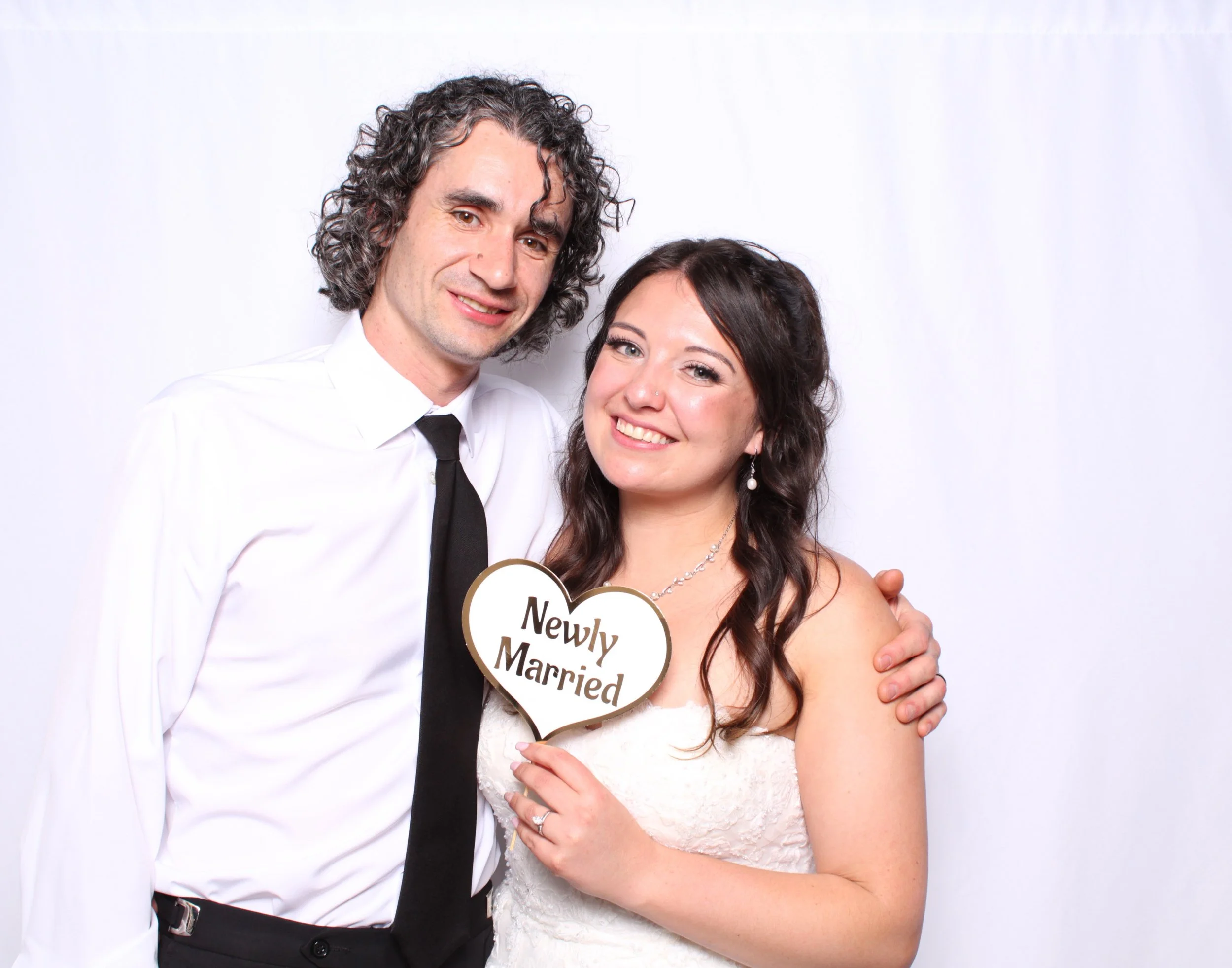 Bride and Groom taking a stunning wedding day photo with event themed props at their Wedding Photobooth that they rented from Insta Prints Photobooth Rentals.