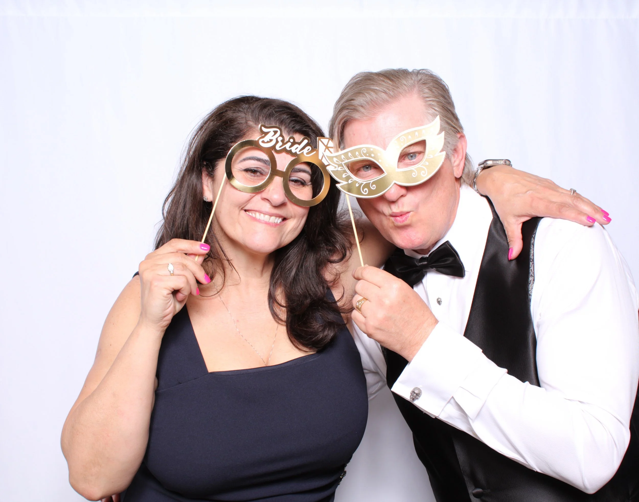 Parents of the Bride having fun taking a photo with wedding themed props at the Photobooth.