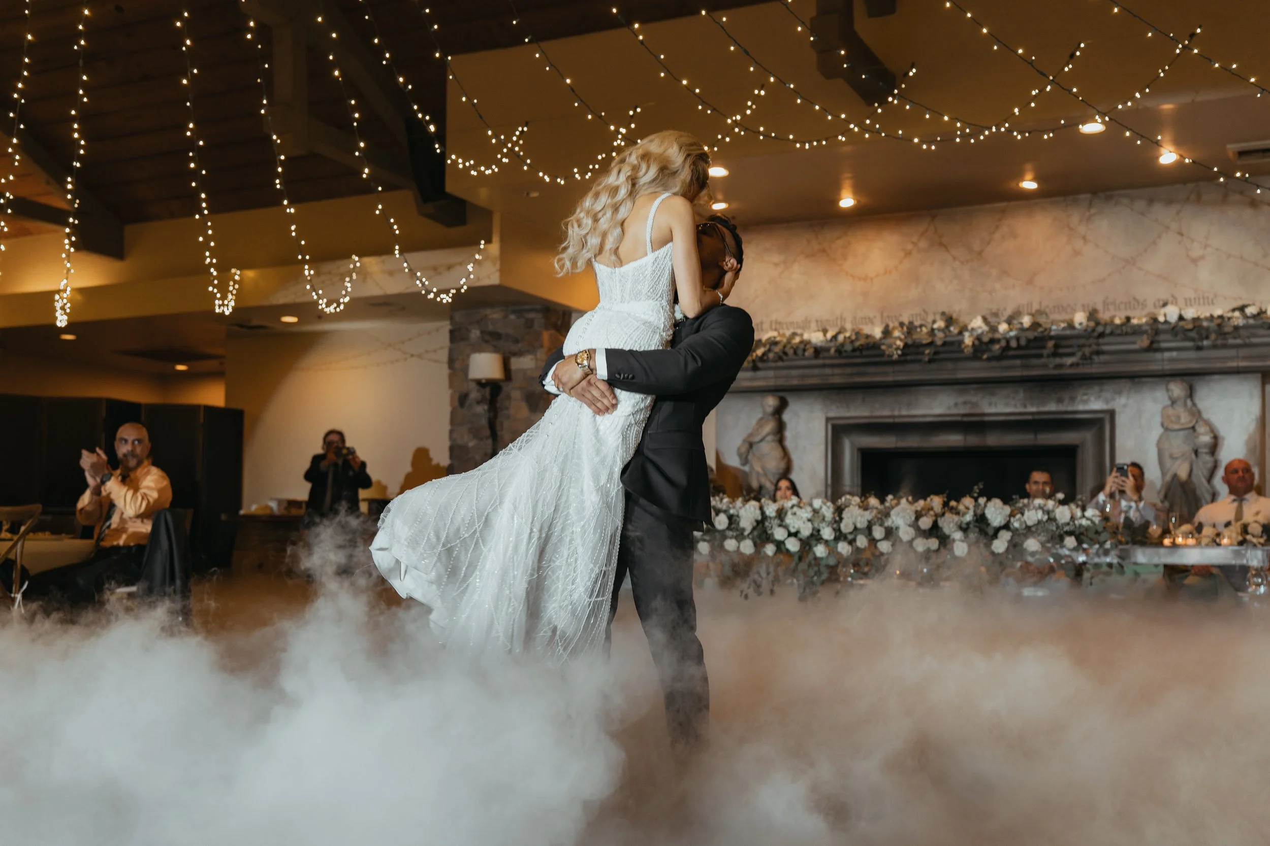 Bride and groom sharing their first dance amid soft lighting and fog during a Bay Area wedding reception, photographed by Lei Photography Collective.