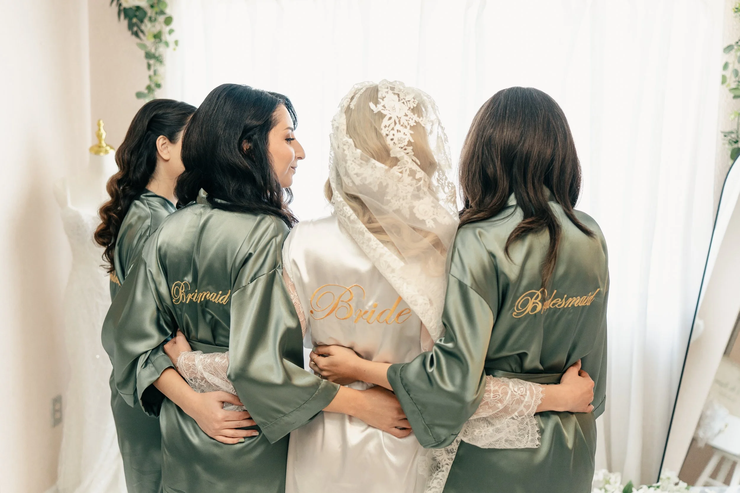 Bride and bridesmaids standing together during wedding preparations in natural light at a Bay Area wedding, photographed by Lei Photography Collective.
